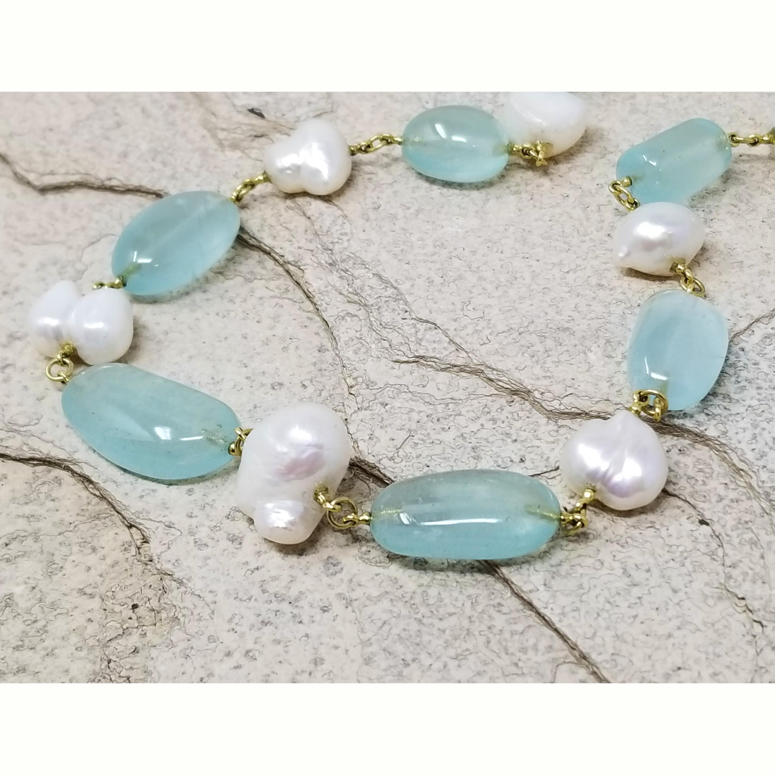 Delicately green-blue hued aquamarines were fashioned into smooth pebbles of varied size and shape for this River Rocks necklace. These were mixed with baroque pearls of varying shapes and sizes, and linked with richly colored 18kt yellow gold. The