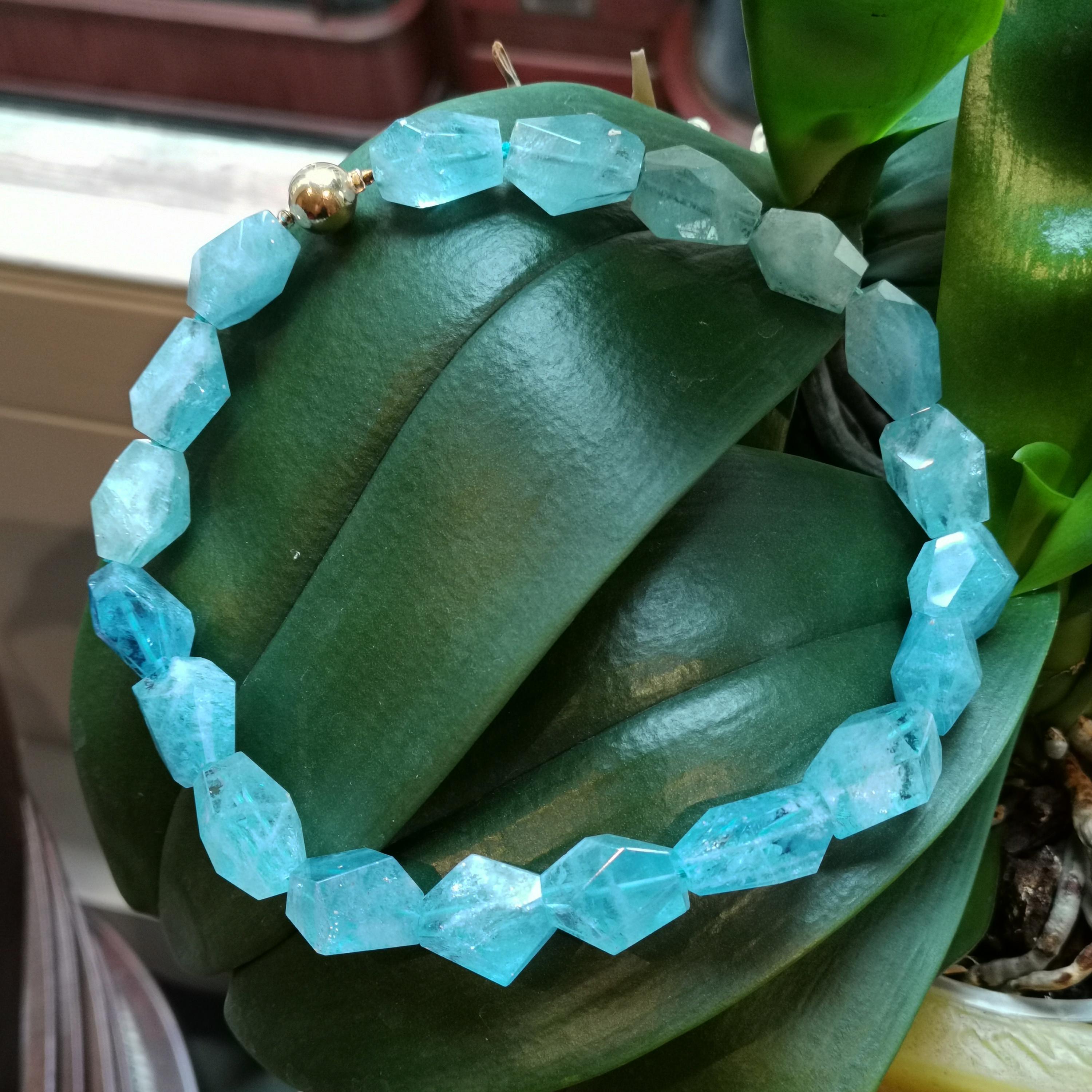 An aquamarine bead necklace, with nineteen beads, each cut as a polished aquamarine crystal and weighing an estimated total of 600cts, strung on blue thread with an 18ct yellow gold ball clasp, gross weight approximately 128 grams, length 43cm / 17