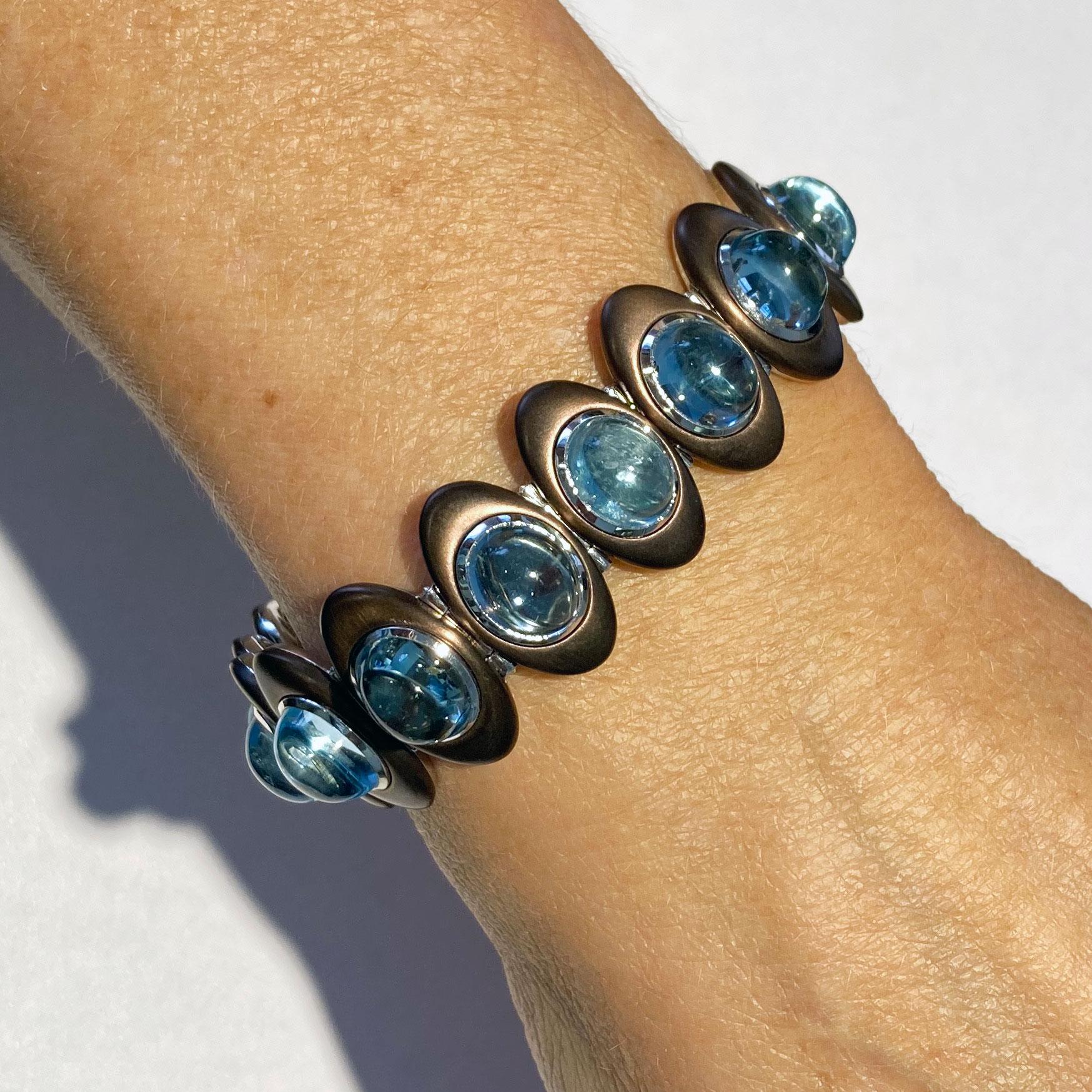 This  18 Kt Withe Gold Bracelet is featuring 17 Aquamarin-Cabochons with a total weight of 52.61 ct in a very modern material combination.The stones are bezelset in 18 Kt white gold, surroundet by a oval shaped frame in ceramic-coated stainless