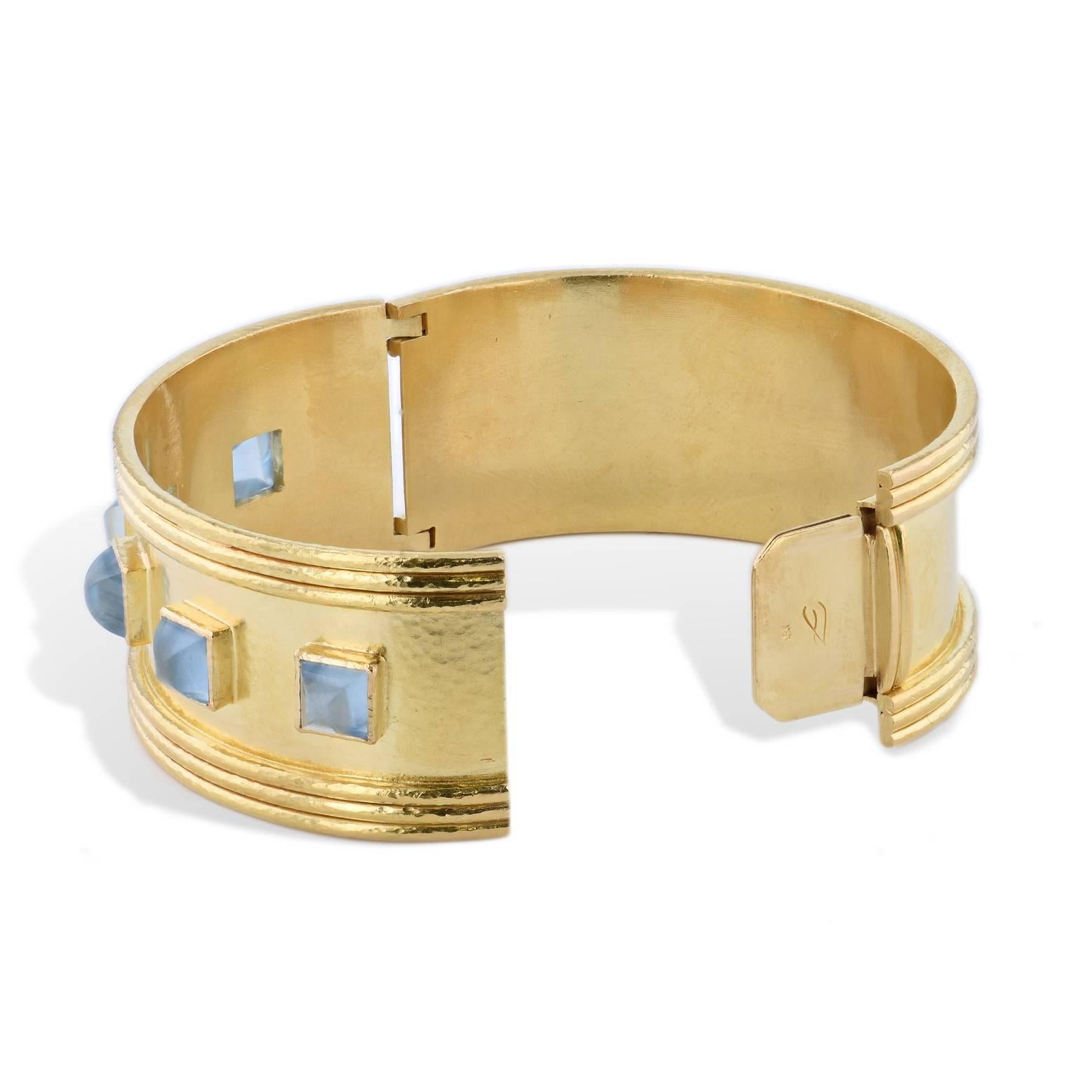 Make a bold statement with this previously loved 18 karat yellow gold twenty-five millimeter hinge bracelet featuring five aquamarine cabochons.