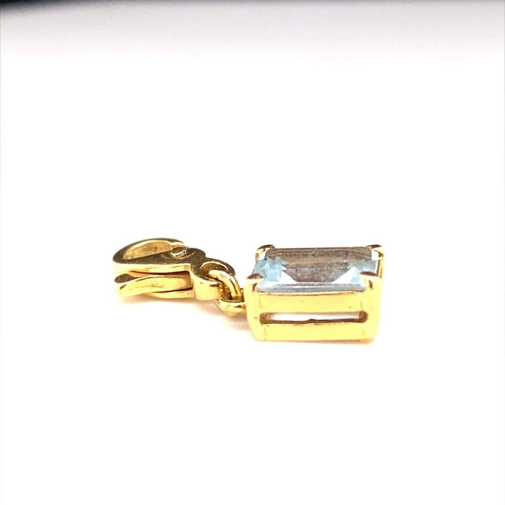 An aquamarine charm pendant in 18 karat yellow gold.

This beautiful retro 18 carat yellow gold charm created as an emerald cut aquamarine to enhance either a bracelet or necklace.

Featuring an emerald cut aquamarine in a four claw double gallery