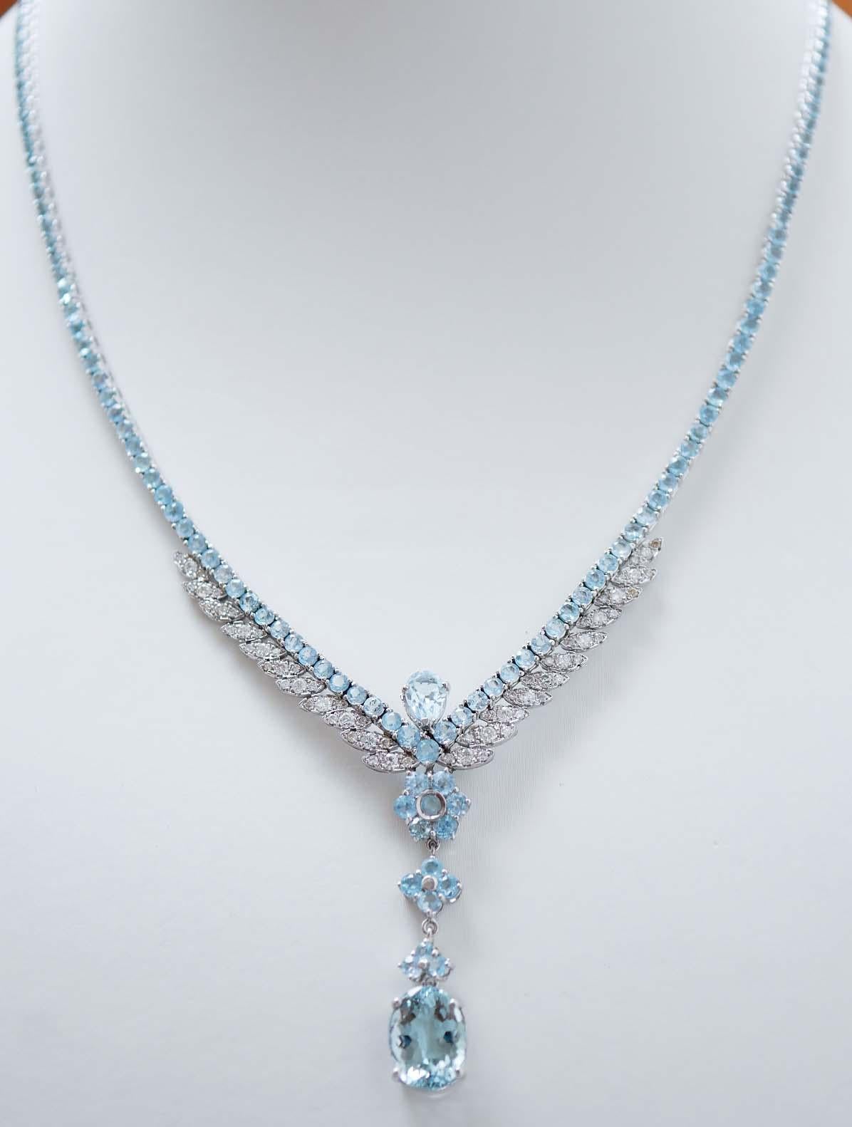 Elegant tennis necklace in 14 kt white gold structure mounted with topaz.
In the fina part, laterally, leaves  studded with diamonds and, as pendant, a flower of topaz. Below, two structures studded with topaz and a pendant of oval topaz.
Diamonds
