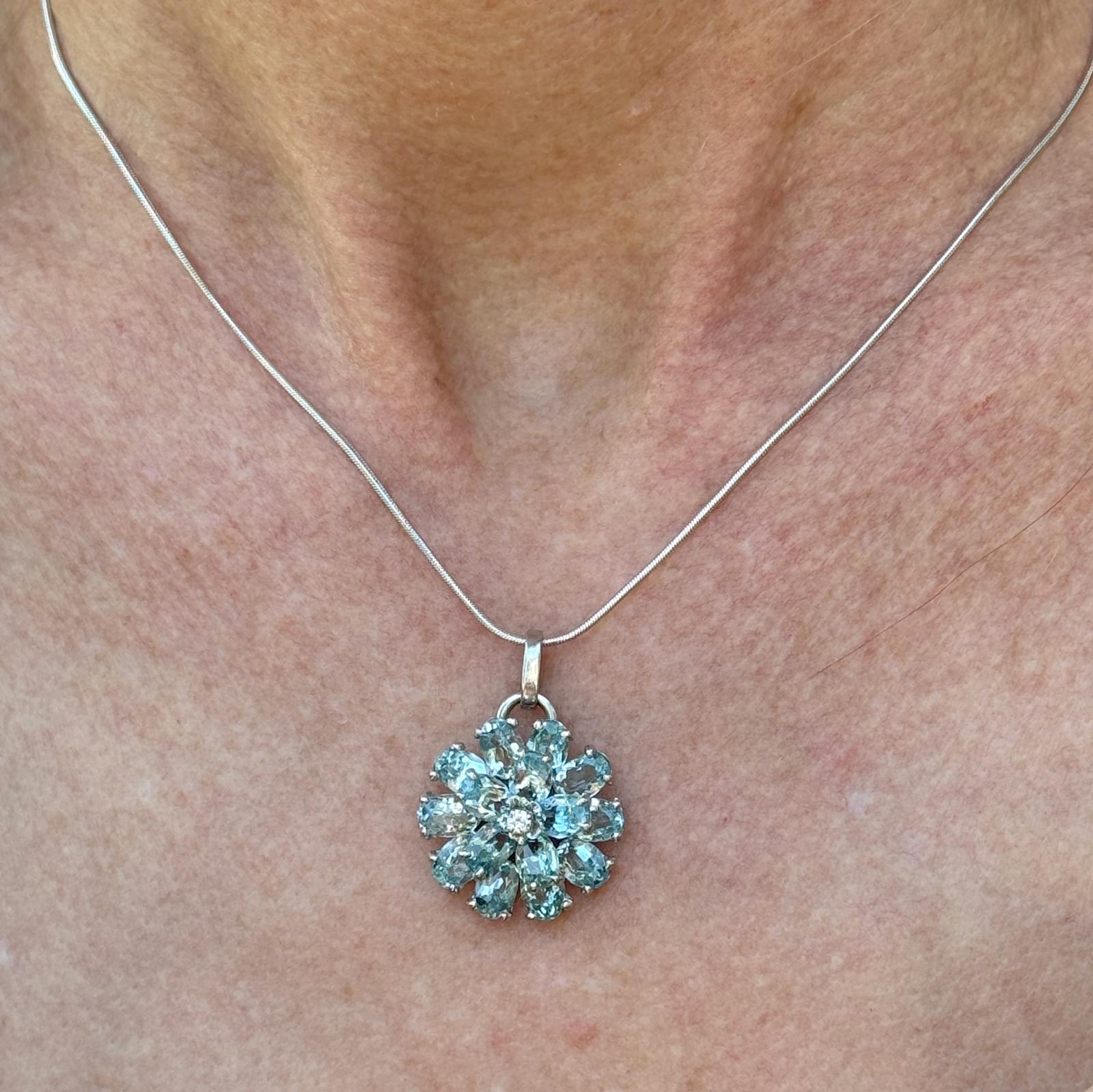 This aquamarine diamond pendant features oval-cut aquamarine gemstones as its centerpiece, known for their serene blue-green hue reminiscent of the ocean. The 16 oval aquamarine gemstones weigh approximately 8.00 carat total weight and are set in a