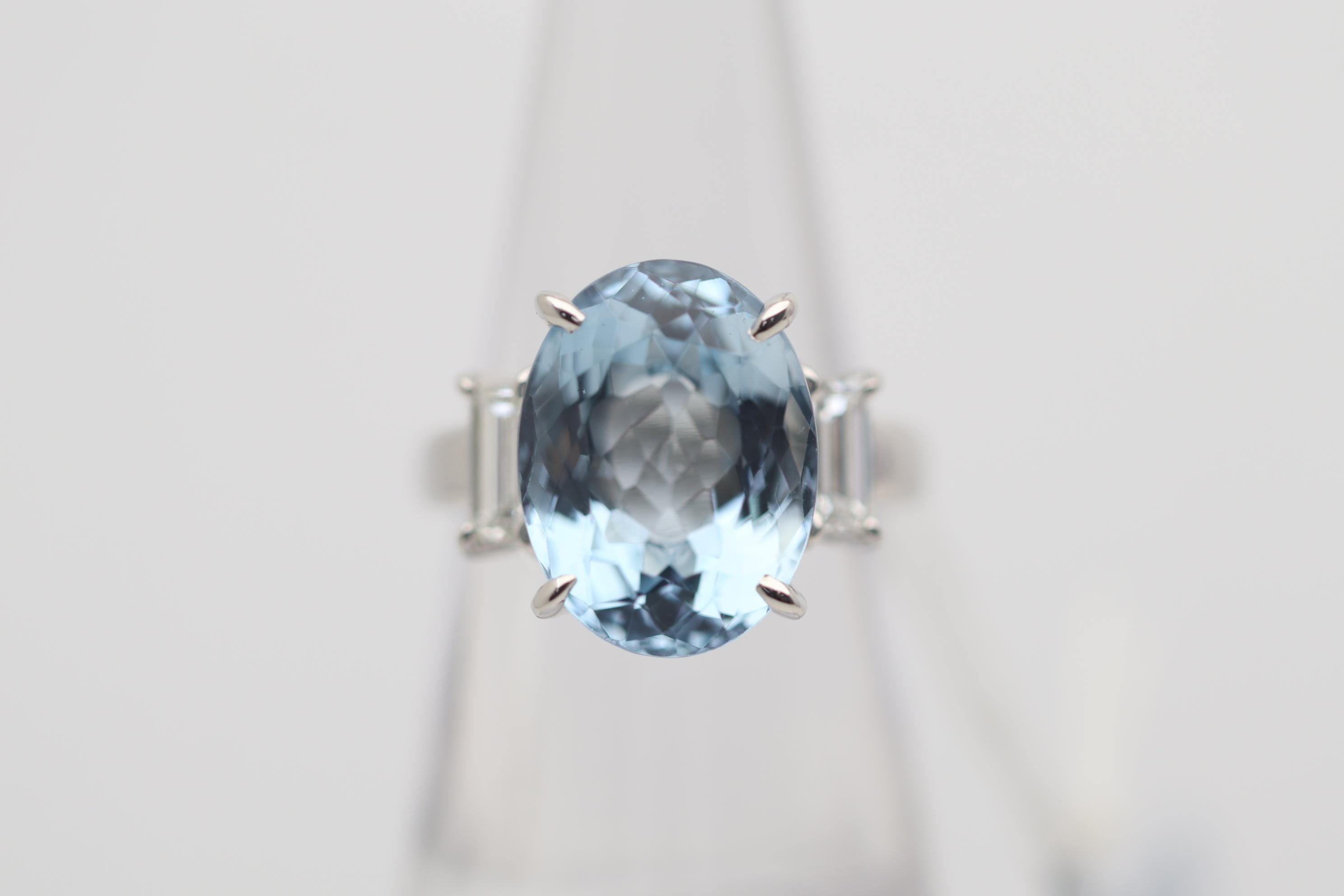 A classic 3-stone ring featuring a large and impressive sea-blue aquamarine weighing 8.28 carats. It has a lovely oval shape and bright clean crystal allowing for great light return. It is complemented by two large baguette-cut diamonds set on its