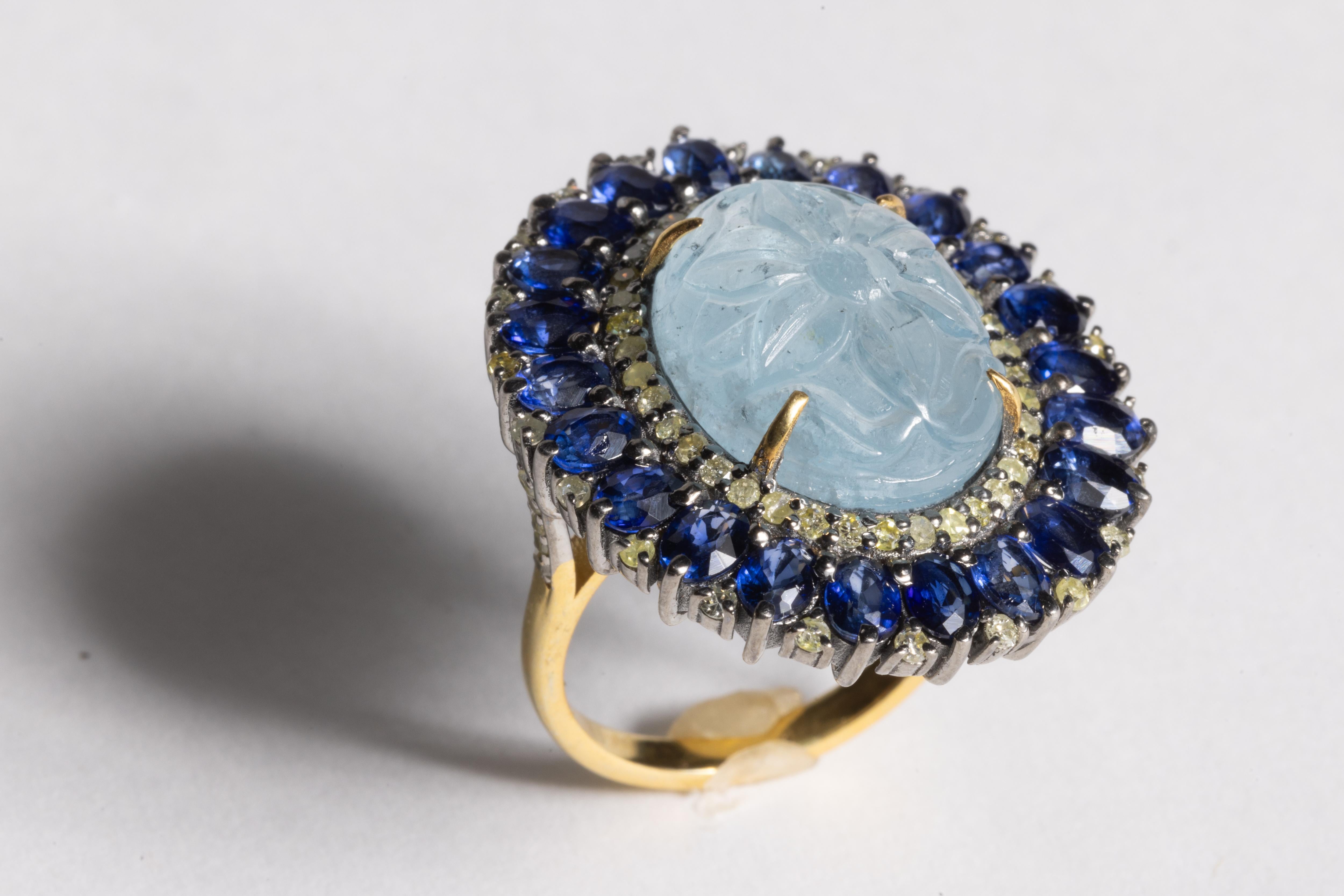 A fabulous and stunning cocktail ring featuring a carved, large oval aquamarine gemstone at the center with a flower motif.  The aquamarine is 11.90 carats.  It is bordered with round, brilliant cut diamonds and then bordered again with faceted,