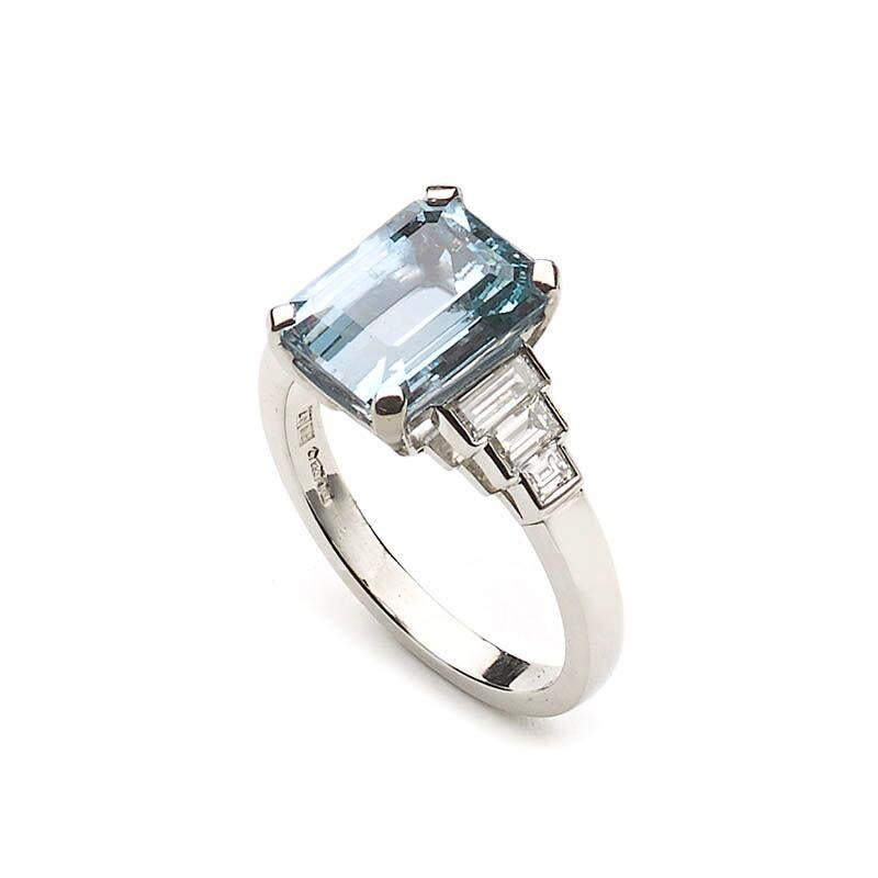 An aquamarine diamond and platinum ring, set with a 3.01ct emerald-cut aquamarine, in a four claw setting, with three baguette-cut diamonds tapering down each shoulder with a total weight of 0.58ct, in rub over settings, mounted in platinum.
Finger