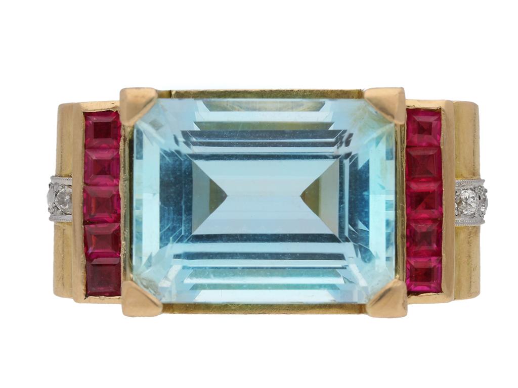 Aquamarine, diamond and synthetic ruby cocktail ring, circa 1945. A yellow gold ring set with one central octagonal emerald-cut aquamarine in a claw setting with an approximate total weight of 25.00 carats, flanked by two rows of ten square step cut