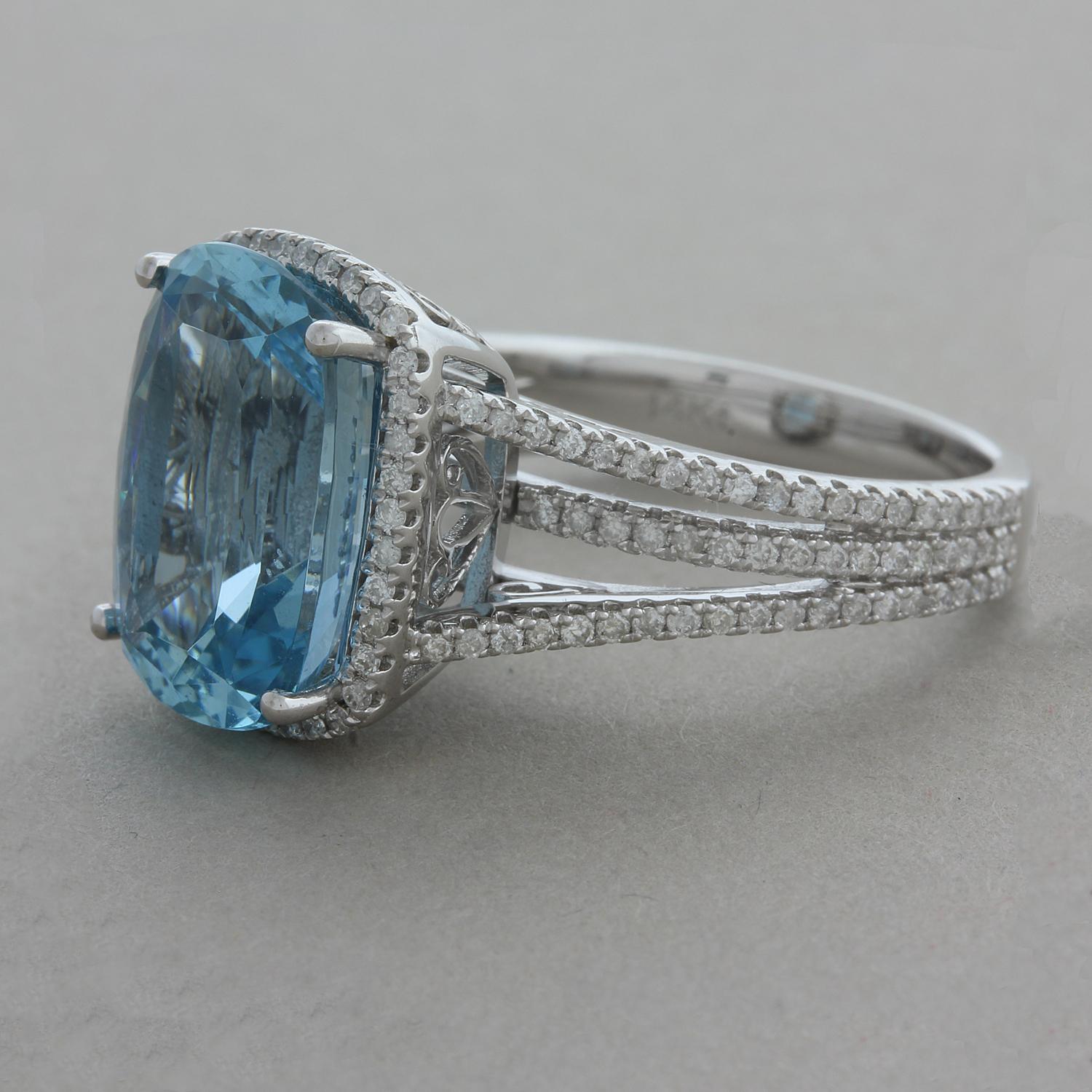 A beautiful gemset ring featuring a 6.17 carat cushion cut aquamarine with a soft sea blue color. The gem is accented by 0.62 carats or round brilliant cut pave set diamonds running along the shoulders of the ring as well as creating a halo around