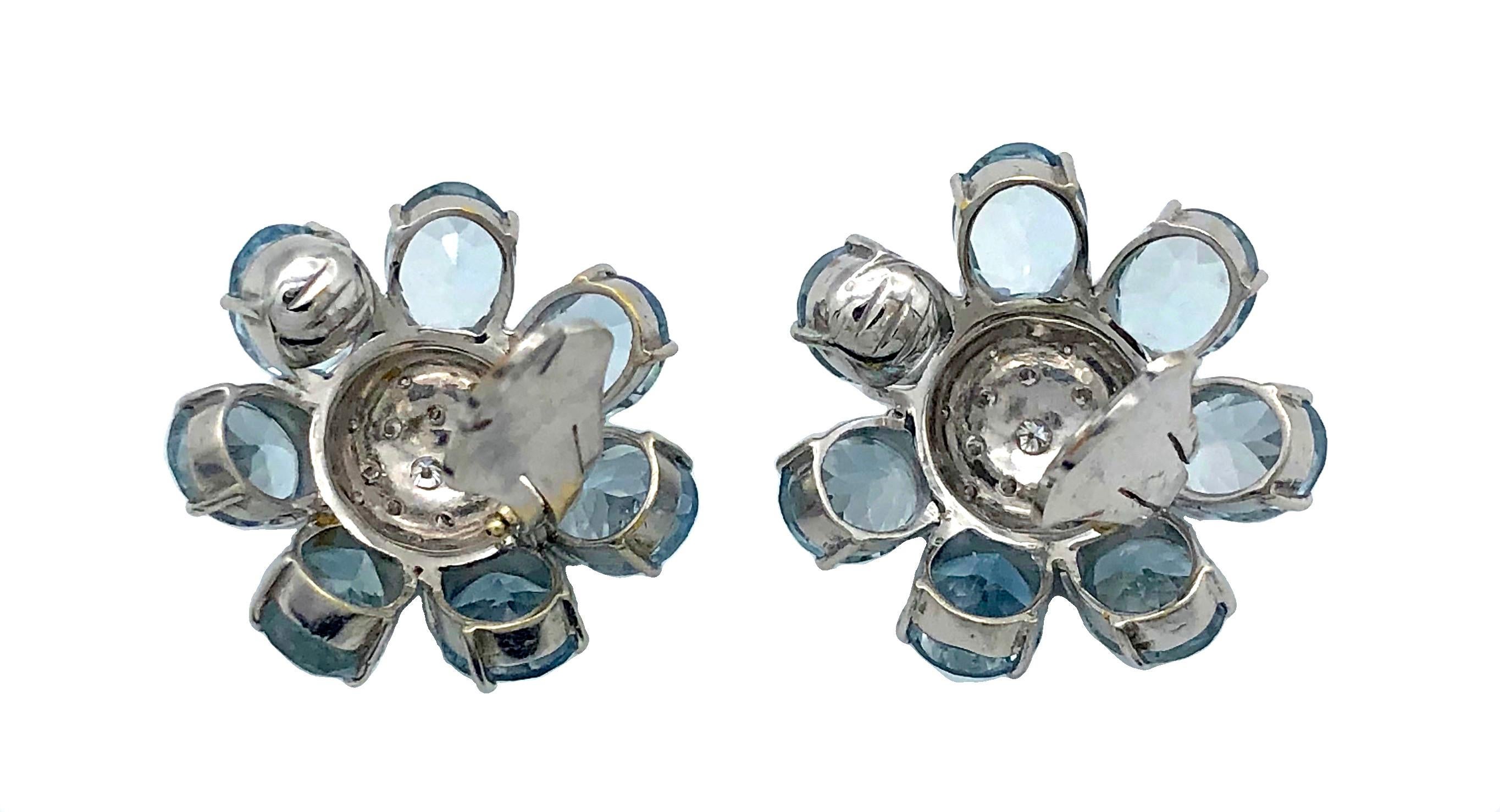 A pair of earclips is designed as two flowers with aquamarine petals. The flowers of the earrings have seven oval facetted aquamarines each with a total weight of 29 ct.  The centre of each flower is engraved with a star. Each centre is set with 15