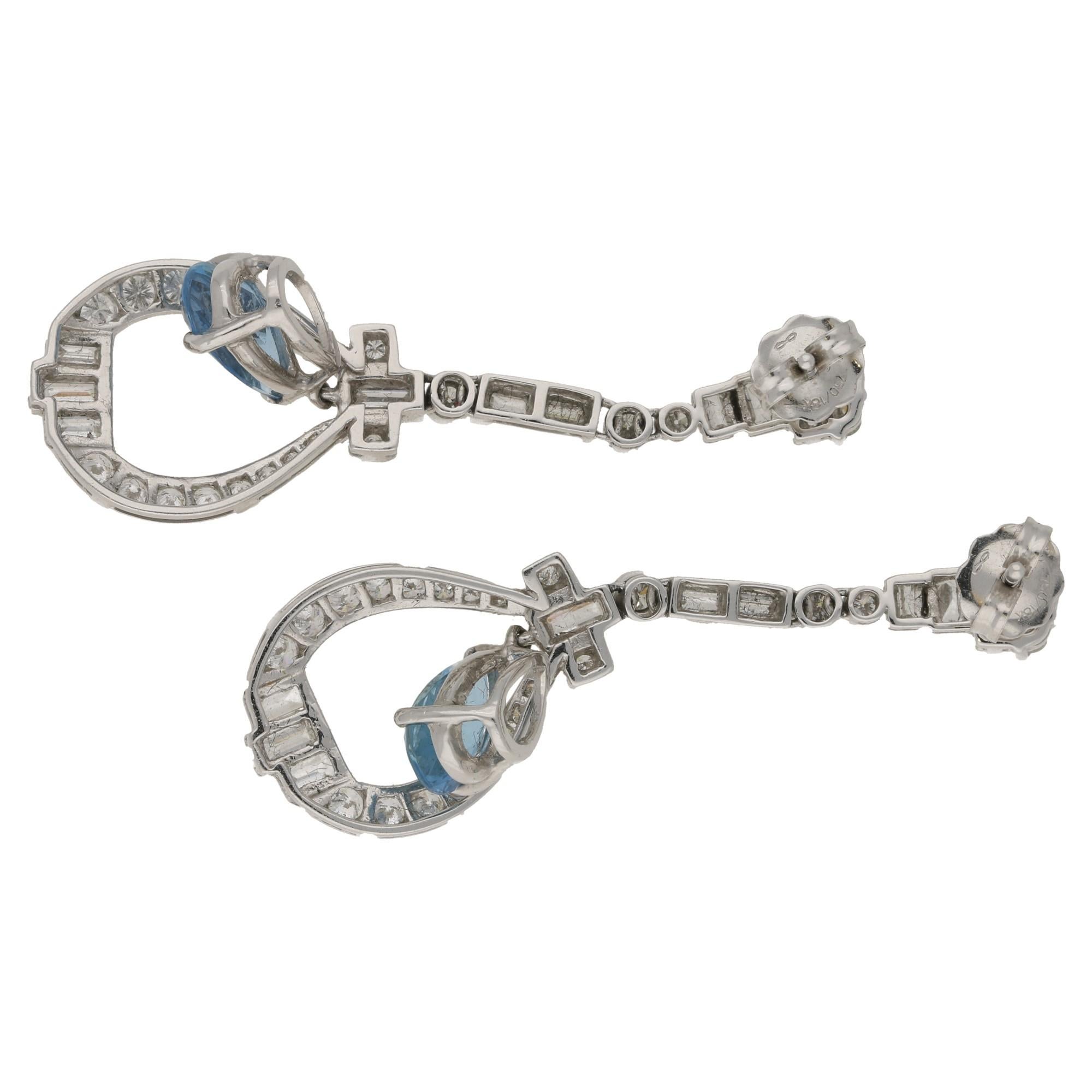  A stunning pair of platinum Art Deco style aquamarine and diamond drop earrings, featuring a mix of round brilliant and baguette cut diamonds in an elegant line from which a pear shaped aquamarine with a vivid sky blue colour measuring 8.9mm by