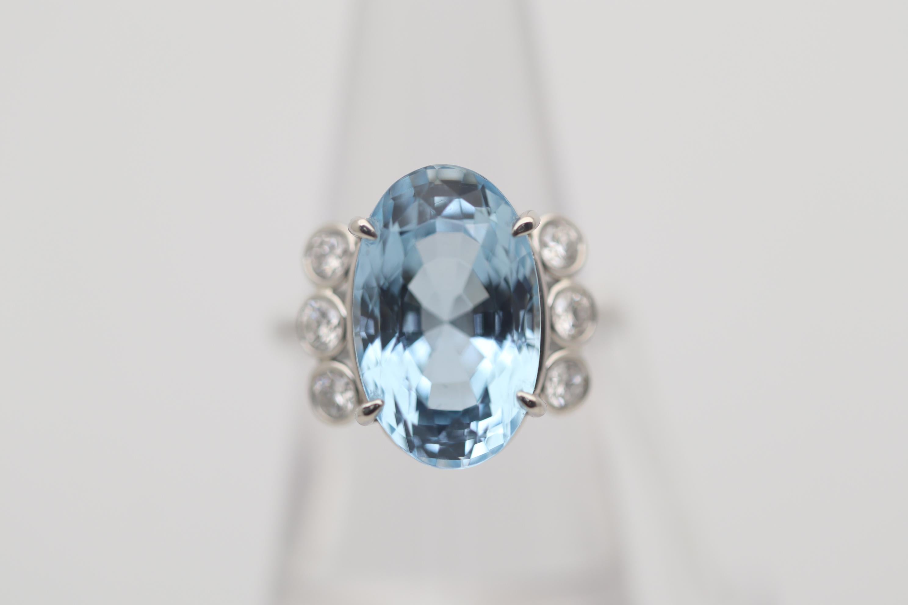 A fine aquamarine weighing 10.96 carats takes center stage of this platinum made ring. The aqua has a bright and lively sea-blue color which is just so pleasing to the eye. It is complemented by 6 large round brilliant-cut diamonds, 3 set on each