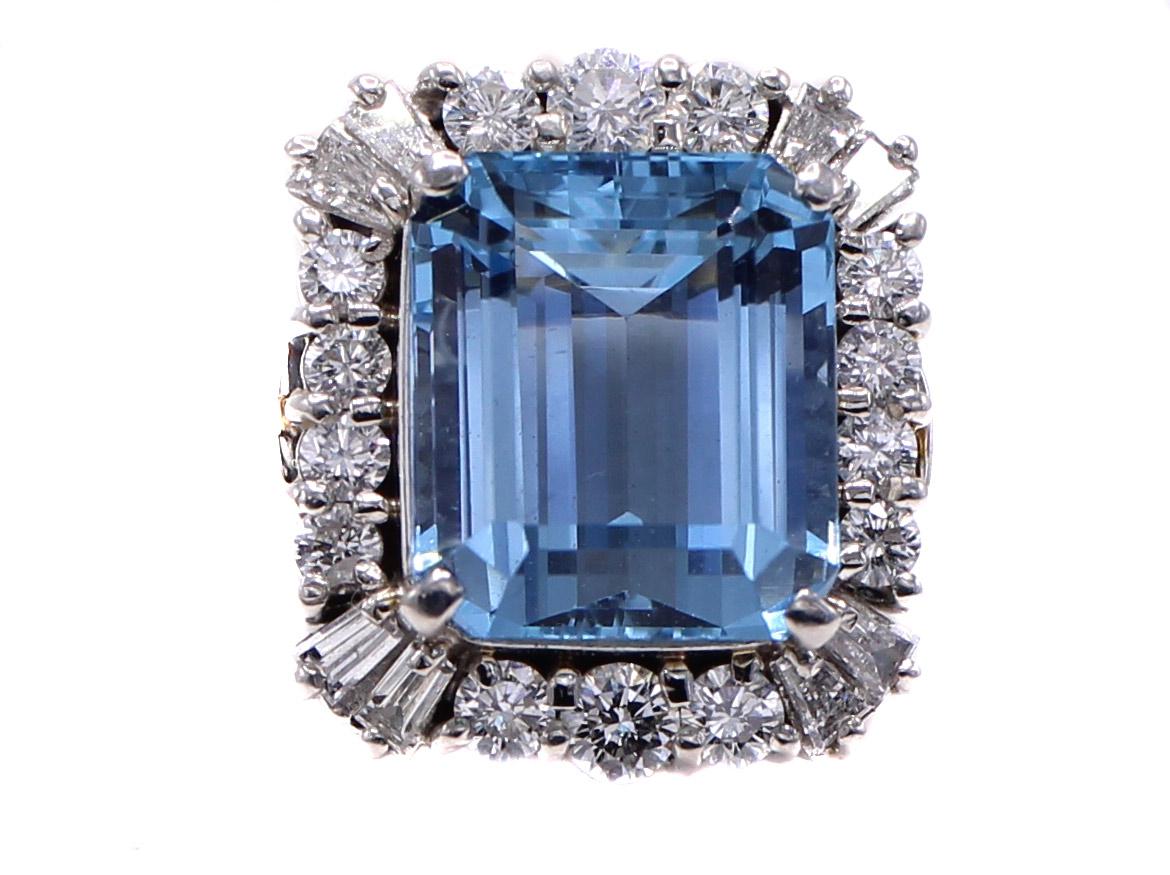 The center piece of this masterfully handcrafted 1970s ring is a gorgeous well saturated emerald cut aquamarine weighing 6.26. The center gem is embellished 14 round brilliant cut and 8 baguette cut diamonds weighing 0.90 carats, all set in
