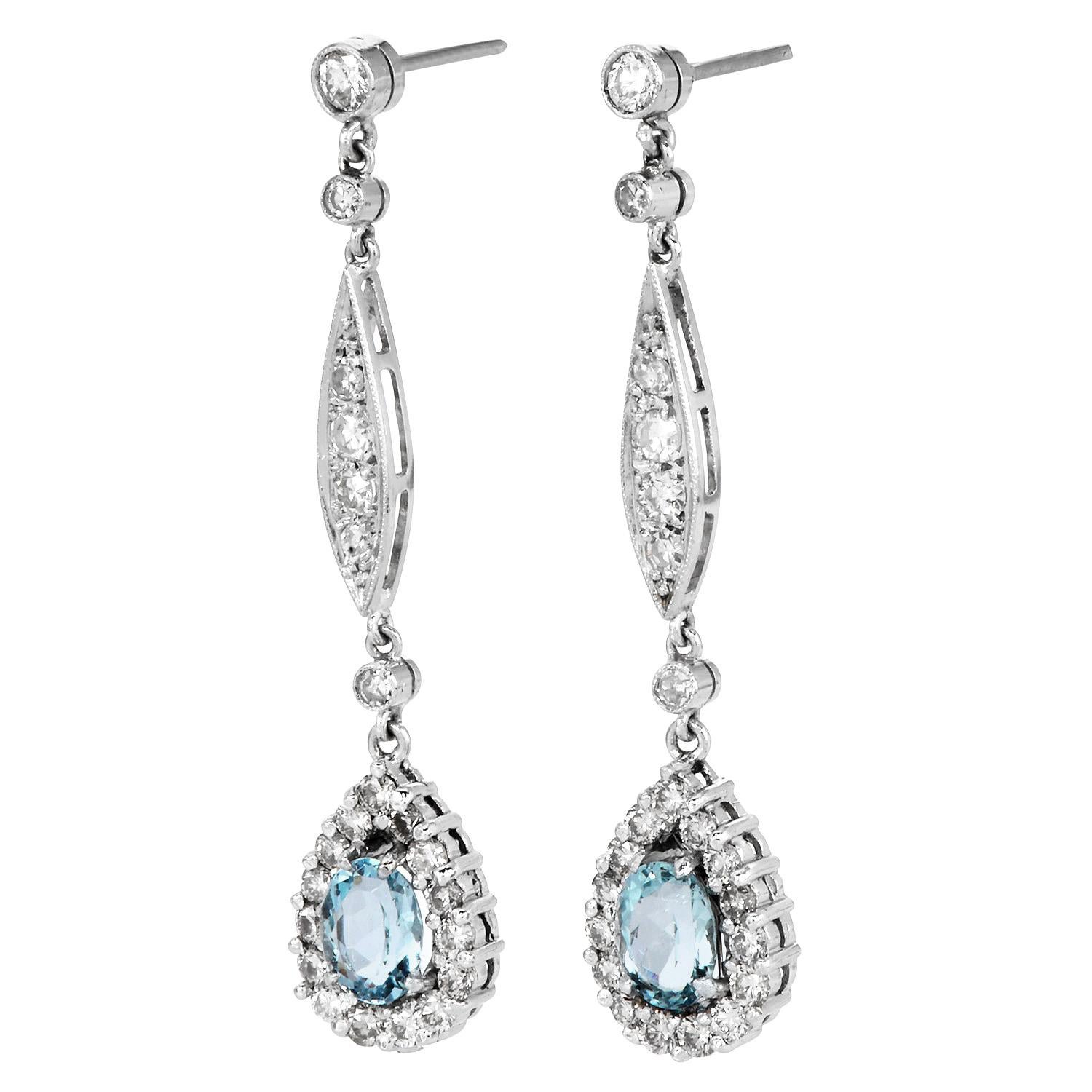 Eleganti e luminosi, questi orecchini pendenti con acquamarina e diamanti sono eleganti. Realizzati in platino, presentano due acquamarine ovali (1,50 carati in totale), ciascuna circondata da un'aureola di diamanti rotondi. Il design a cascata è