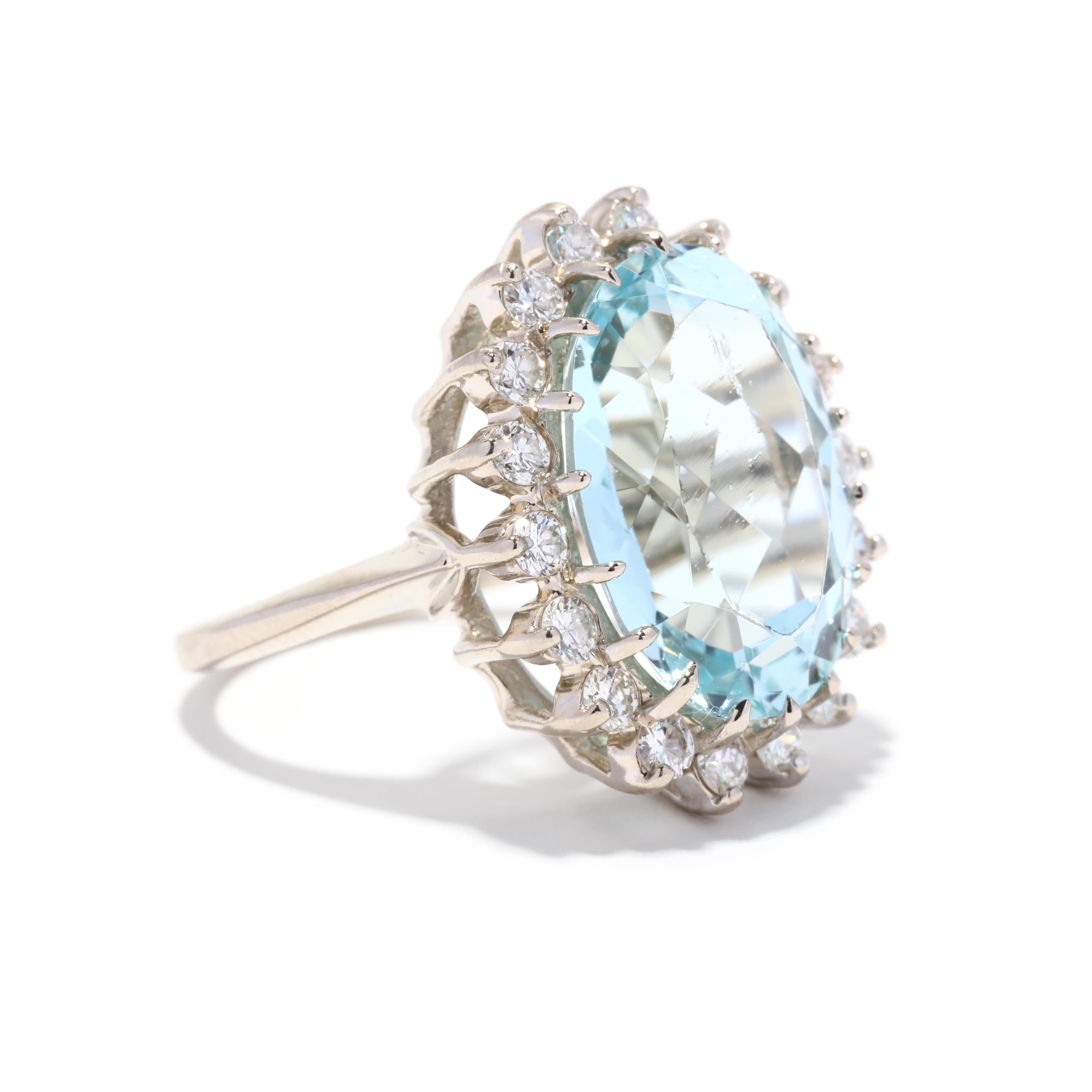 A vintage 14 karat white gold large aquamarine and diamond halo ring. This cocktail ring features a prong set oval cut aquamarine weighing approximately 9 carats surrounded by a halo of round brilliant cut diamonds weighing approximately 1 total