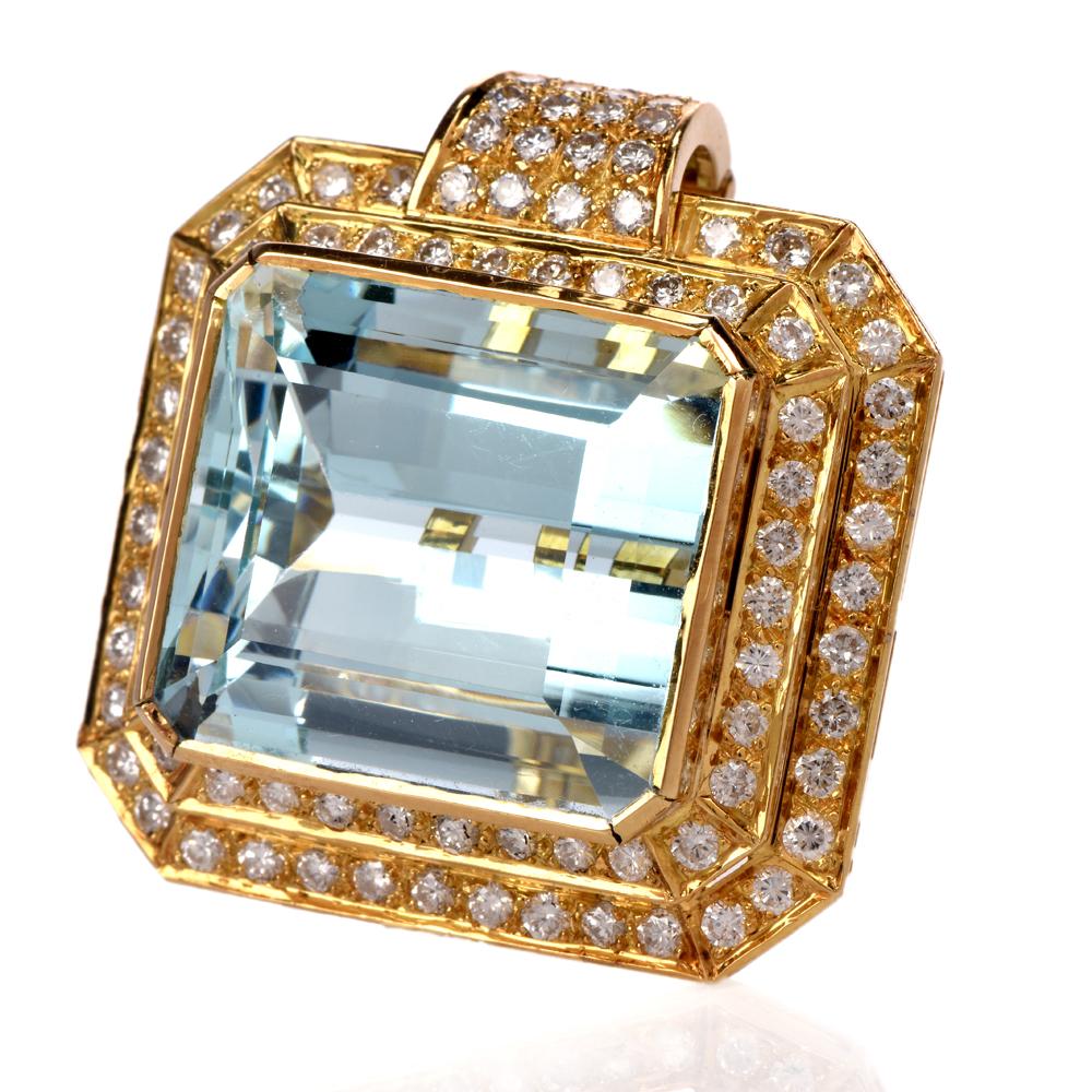 This elegant 1970's aquamarine and diamond pendant is crafted in solid 18-karat yellow gold. Displaying a prominent centered emerald-cut bezel set aquamarine weighing approx. 28.18 carats. Surrounded by a double halo and bale prong set with 100