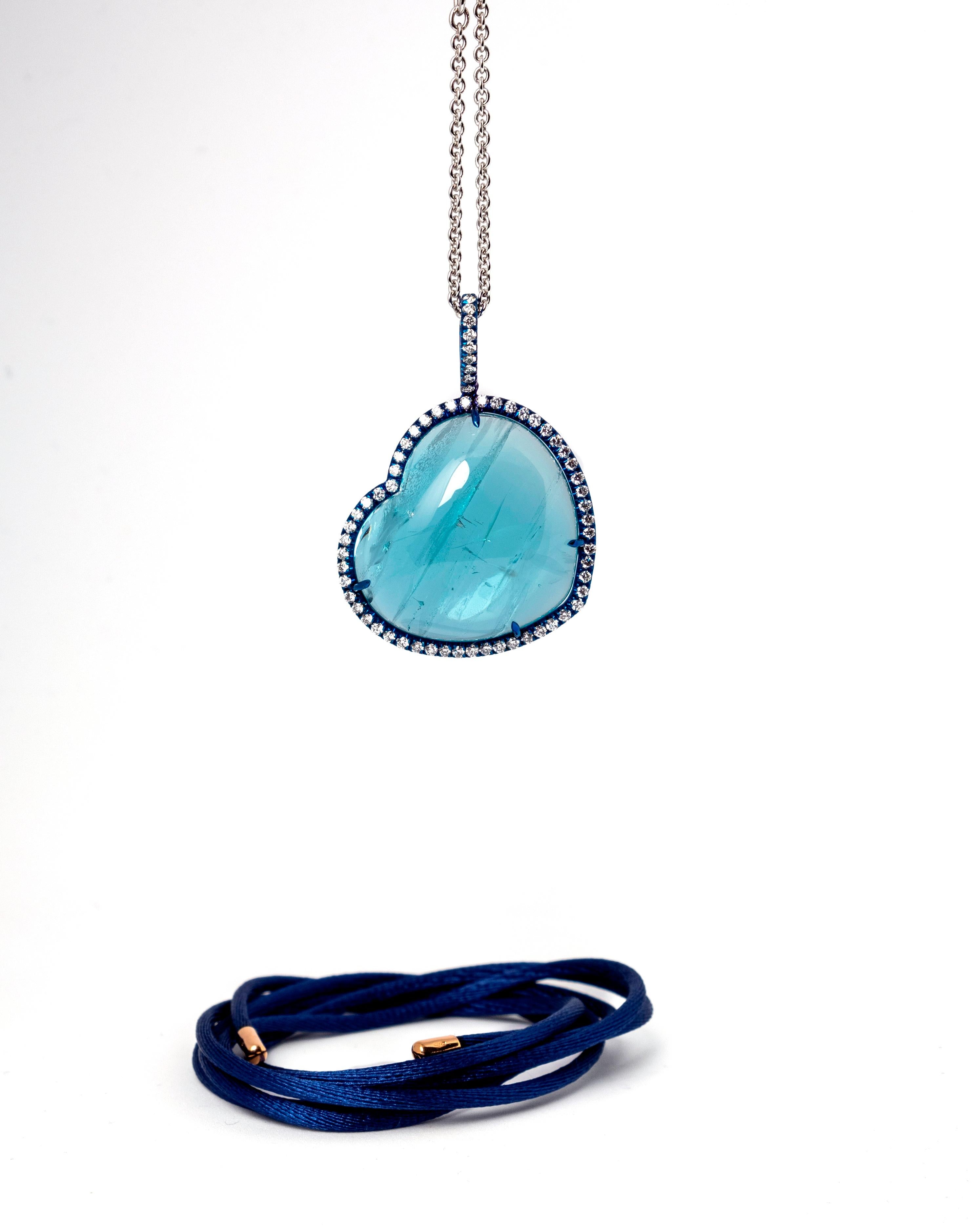Handcrafted in Margherita Burgener family workshop, the lovely pendant with chain features as main stone a Brazilian cabochon cut 44.57 carat aquamarine.
The stone is unique, especially due to the lovely natural inclusions.
A line of blue titanium
