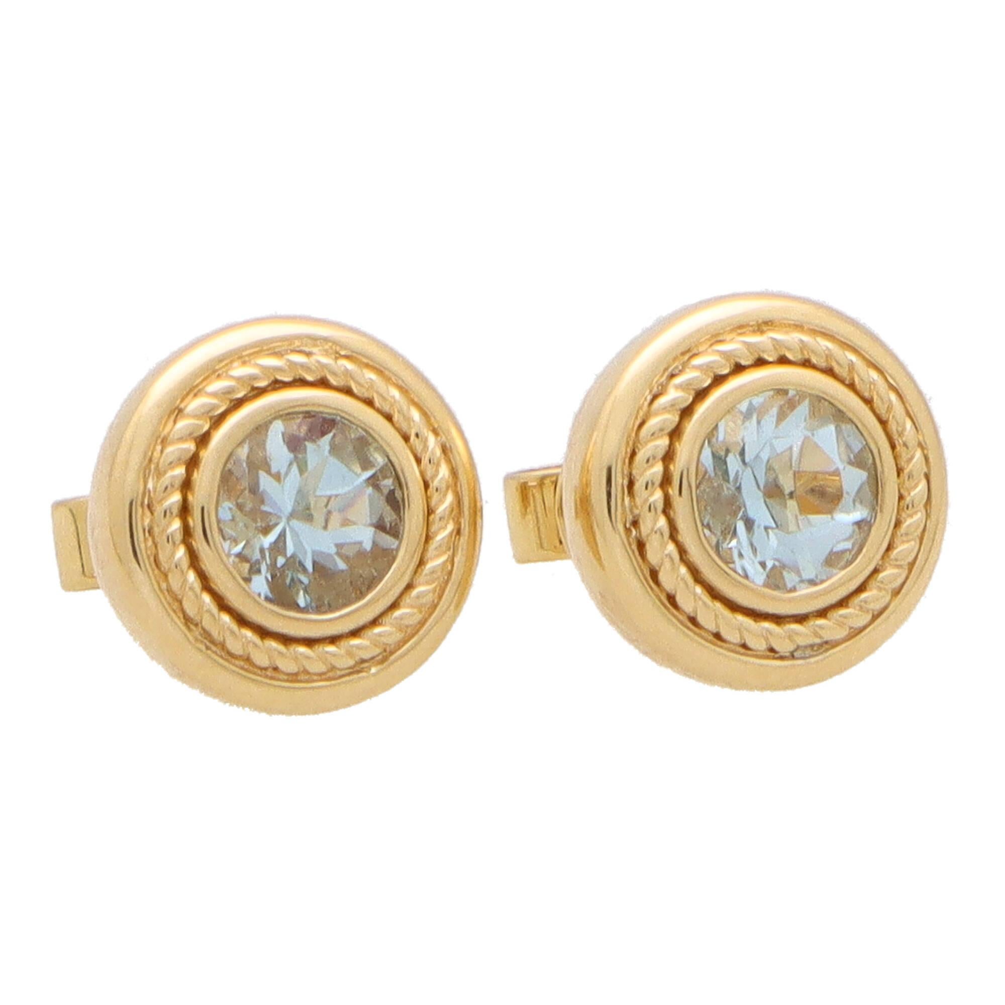 An incredibly stylish pair of Etruscan inspired aquamarine stud earrings set in 18k yellow gold.

Each earring is solely set with a 0.45 carat round cut light blue aquamarine which is securely set in a chunky yellow gold rub over setting. The edging