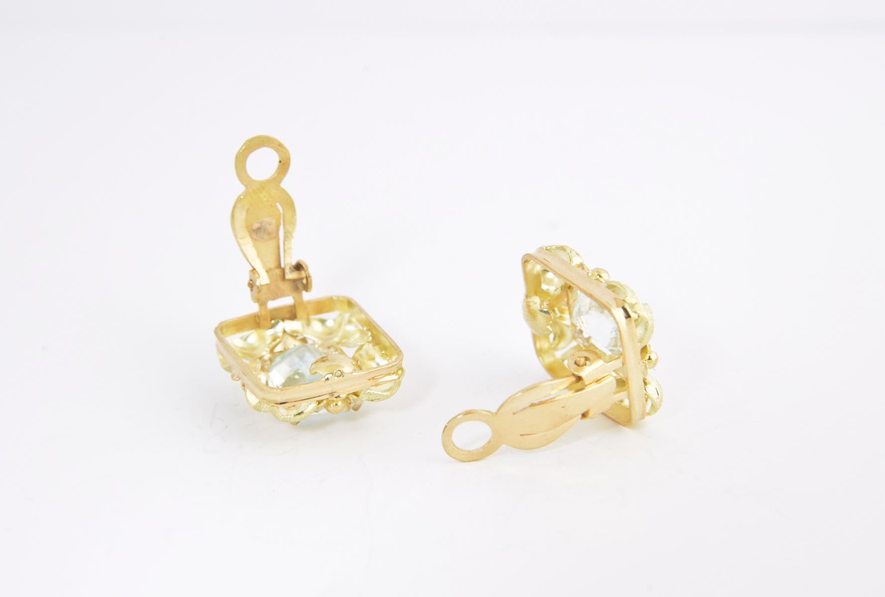 18K green and rose gold frame earrings with flowers and leaves surrounding emerald-cut aquamarine centers. Clip backs.
