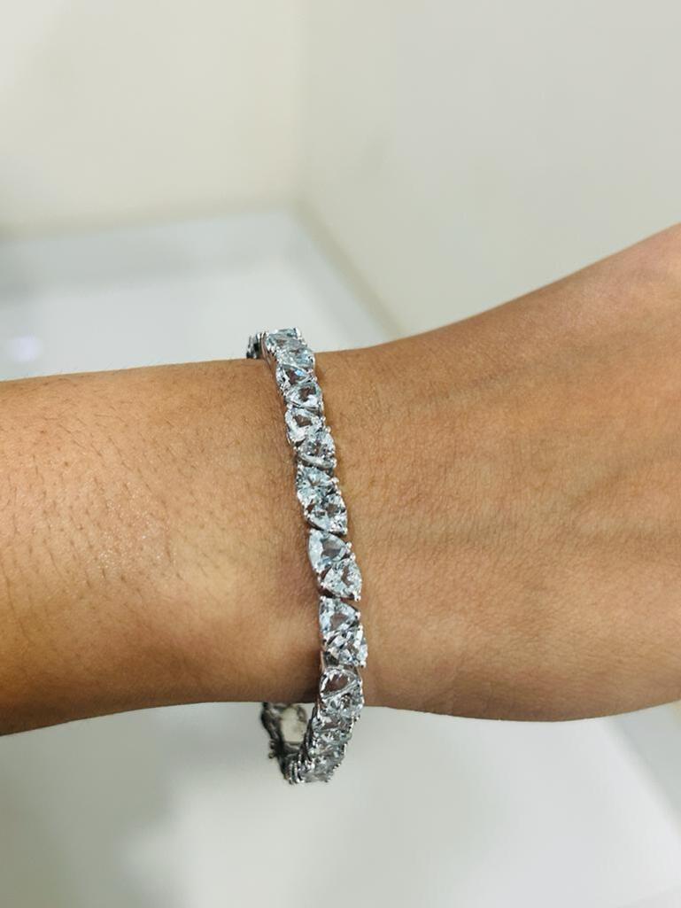Le bracelet de tennis en argent sterling orné d'aigue-marine met en valeur une aigue-marine naturelle d'un poids de 21,12 carats, étincelante à l'infini. Il mesure 7.5 pouces de long. 
L'aigue-marine stimule la concentration et réduit le stress.