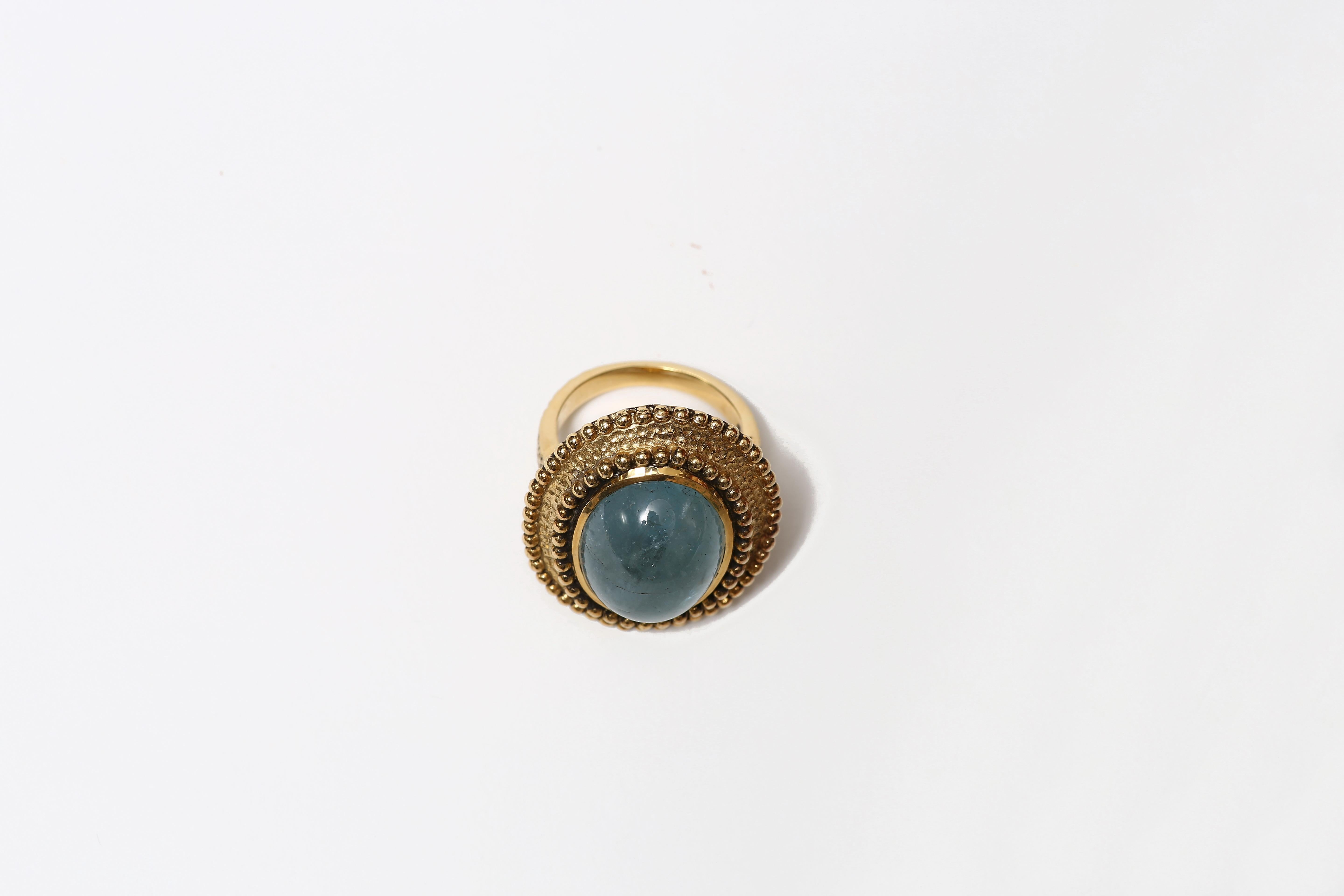A beautifully handcrafted ring  with oval cabachon aquamarine set in 18 karat gold frame with decorative beaded edges.
US size: 7.75
Interior: 1.6cm dia 

Designed by AMANDA CLARK for Altfield, our collection focuses on natures most lovely materials