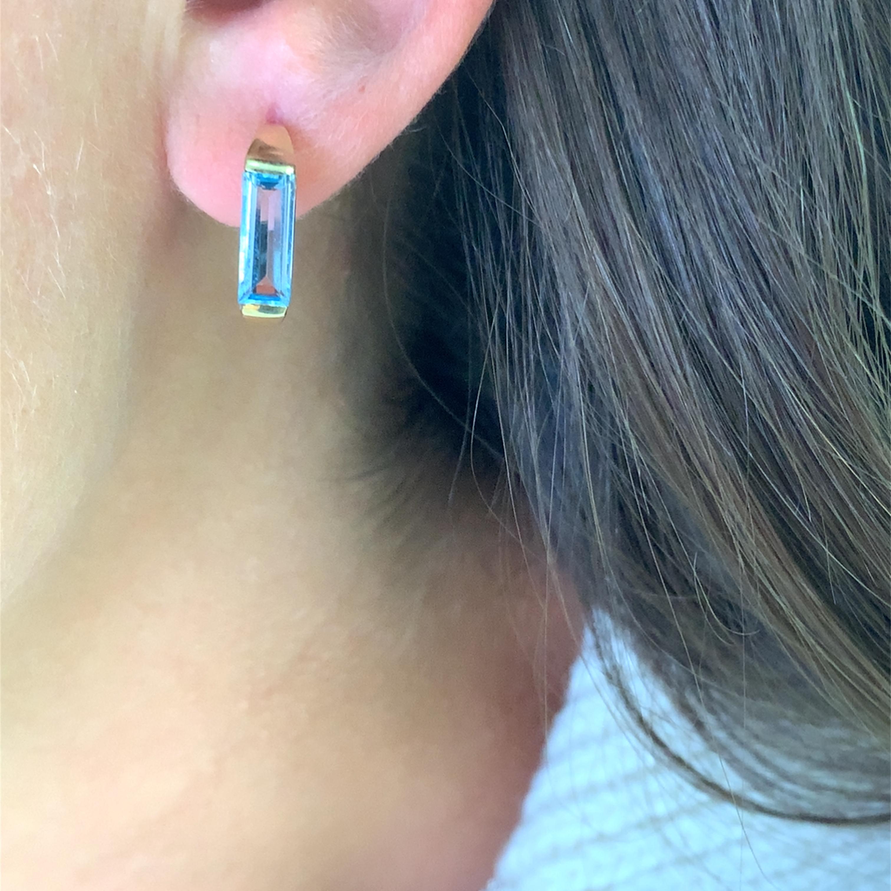 Eleganti orecchini in oro giallo con acquamarine taglio smeraldo da 2,20 carati in totale. Le fresche gemme blu offrono un accattivante contrasto con il tono caldo dell'oro giallo 14k. L'acquamarina misura circa 10x4mm, gli orecchini hanno un