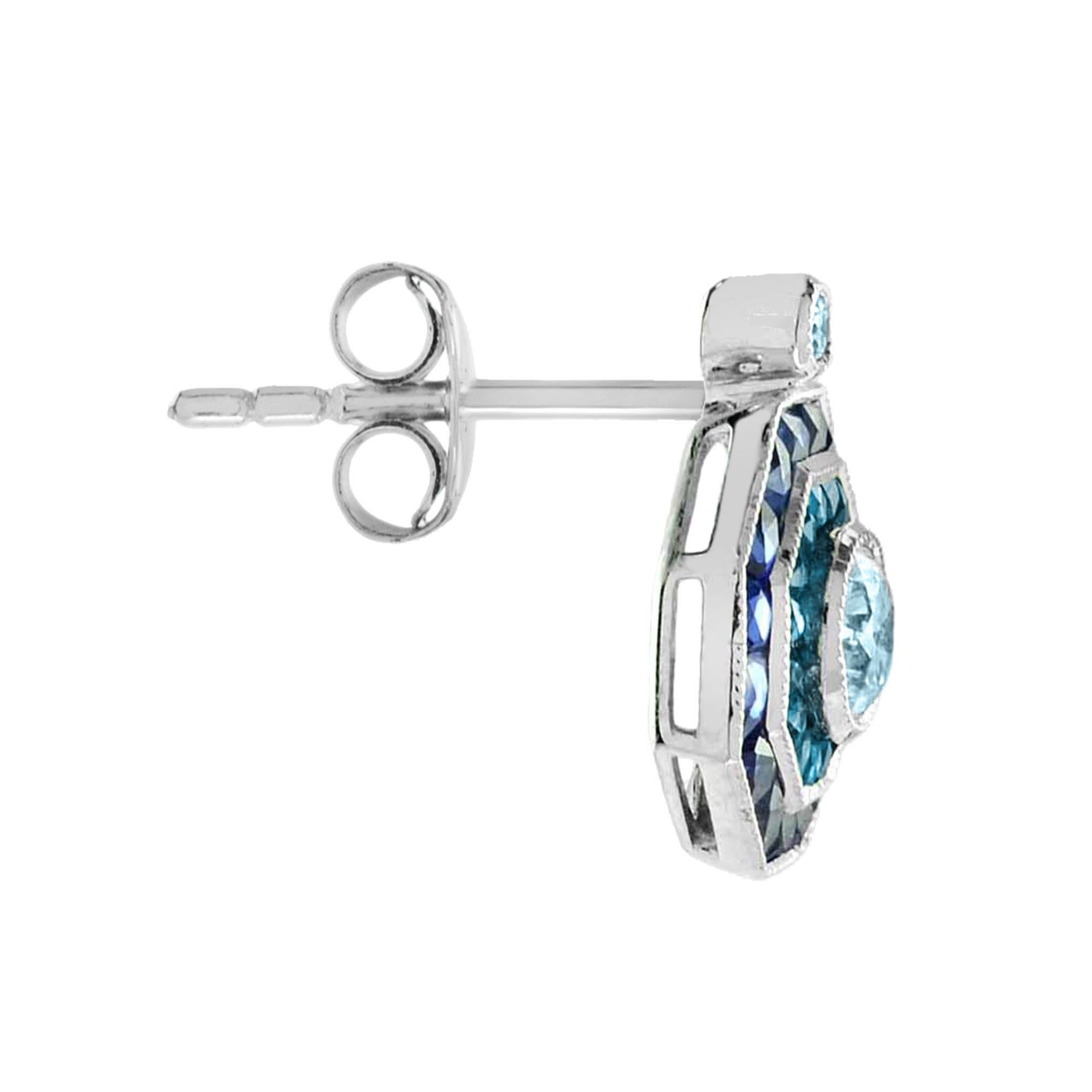 Les boucles d'oreilles cibles d'inspiration Art Déco sont serties d'une superbe aigue-marine, encadrée d'une bordure octogonale de topaze bleue de Londres taillée à la française et d'autres saphirs bleus qui s'enroulent autour de la bordure. Or