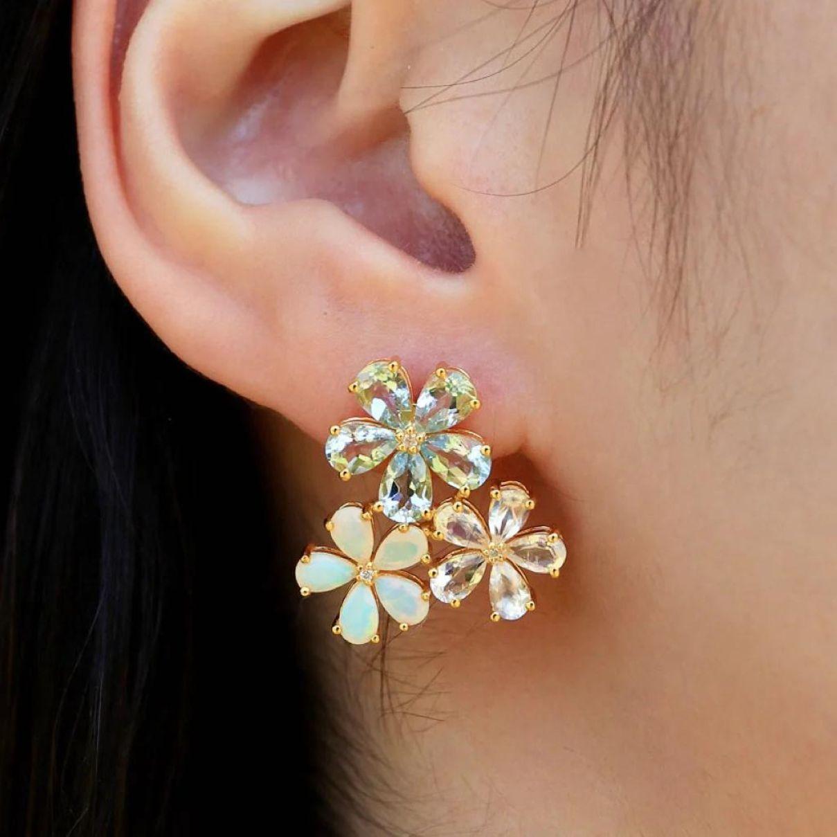 Crafted with an artistic flair, each earring features radiant aquamarine, ethereal moonstone, iridescent opal, and sparkling diamonds, symbolizing the delicate petals of a blossom in full bloom. The soft, serene hues of aquamarine and moonstone