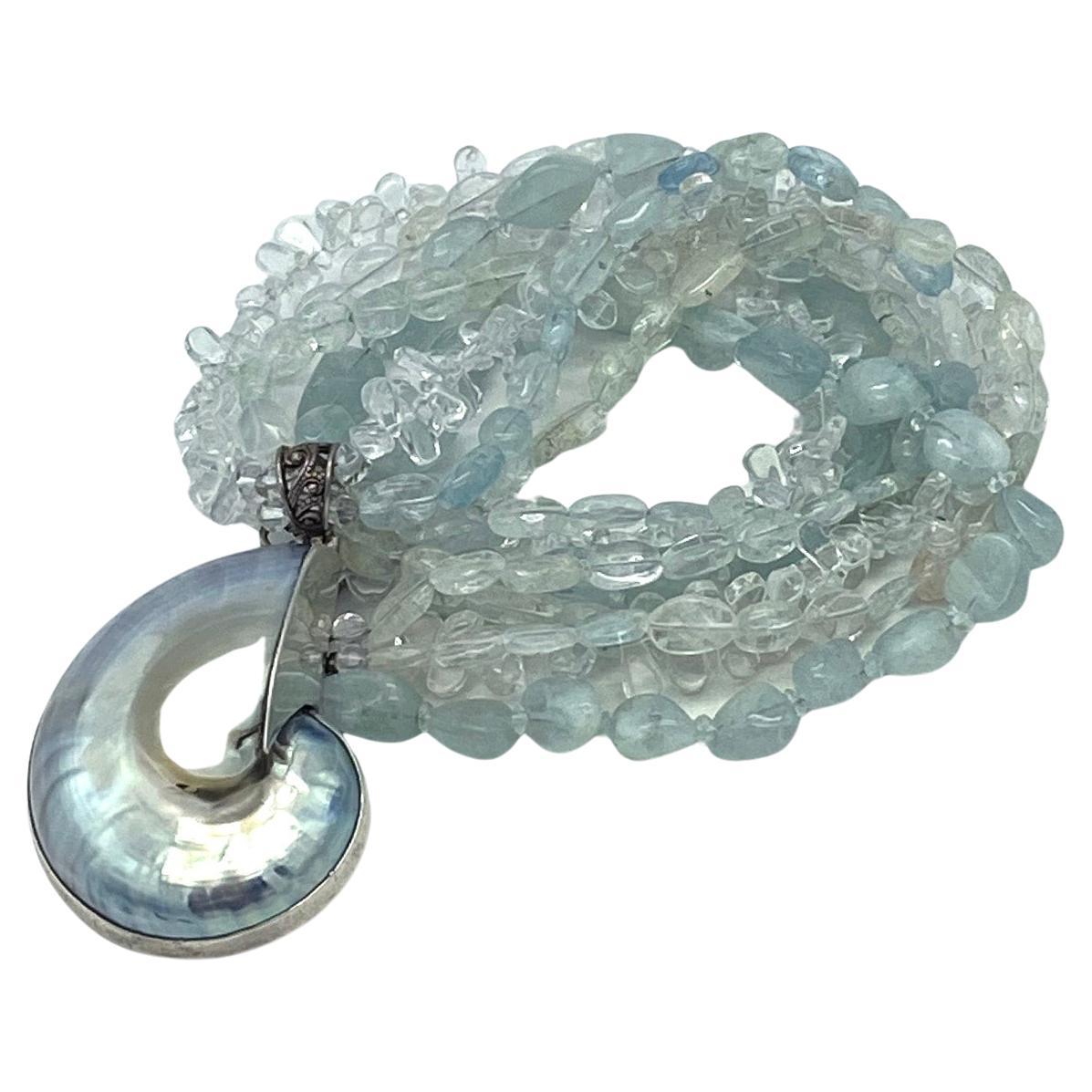 This is a multi-strand aquamarine (with a mixture of transparent to opaque stones) necklace with an ammonoidea (1.63 x 2.25 x 0.75 inch) pendant in sterling silver frame and with a toggle clasp. 

Our vintage jewelry collection and original