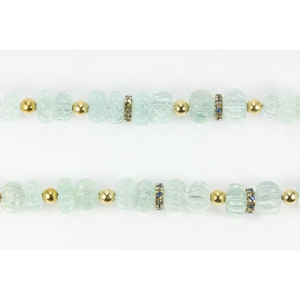 Una magnifica collana di acquamarina e zaffiri. Questo pezzo intagliato a mano vanta un design unico e seducente che non mancherà di raccogliere complimenti. Cinquantacinque perle di acquamarina sono elegantemente infilate con perline d'oro tra le