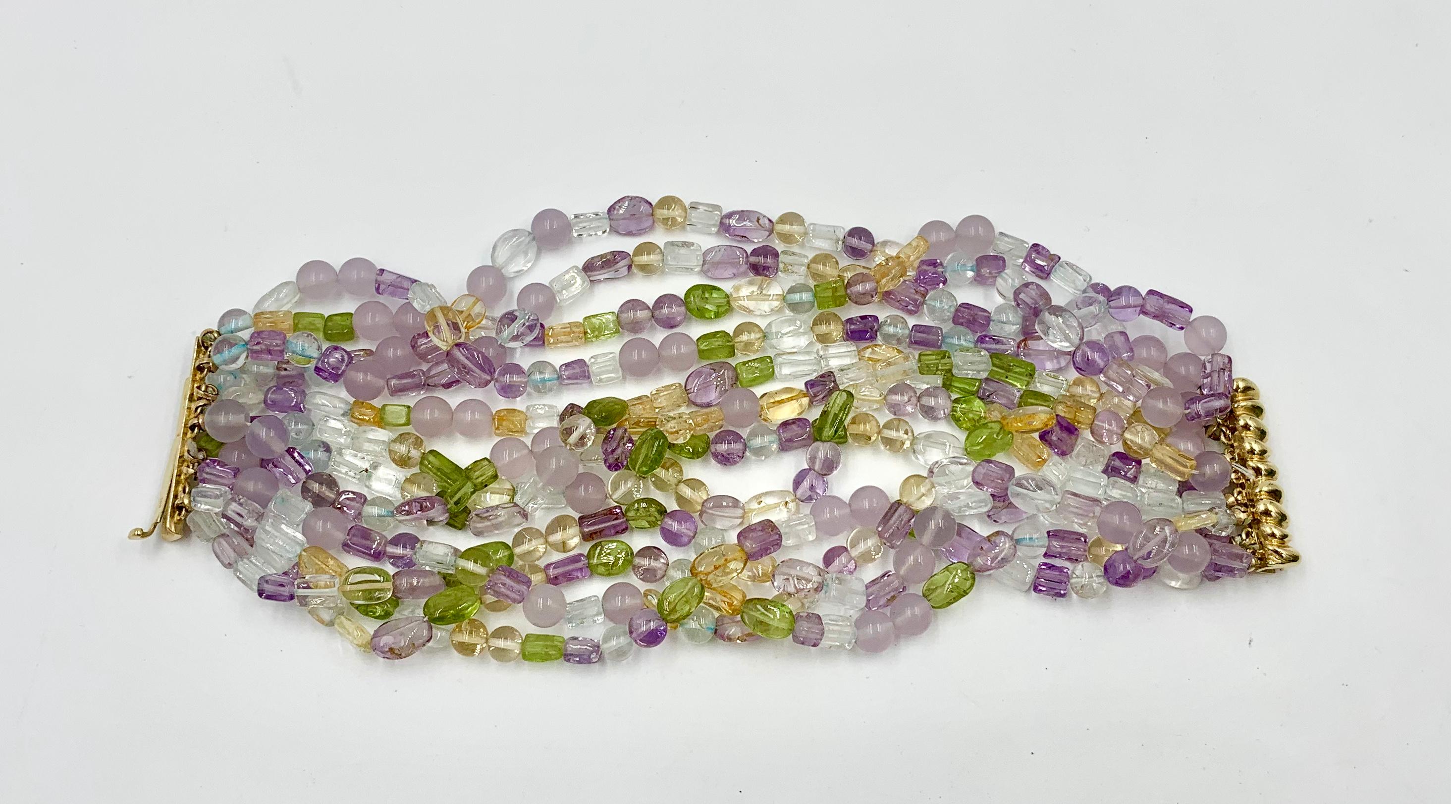 Indulge in a stunning Multistrand Multicolored Bead Torsade Bracelet with 12 strands of Amethyst, Peridot, Citrine & Aquamarine beads with a 14 Karat Gold clasp.  The stunning Multigem Bracelet is set with round, rectangular and oval Aquamarine,