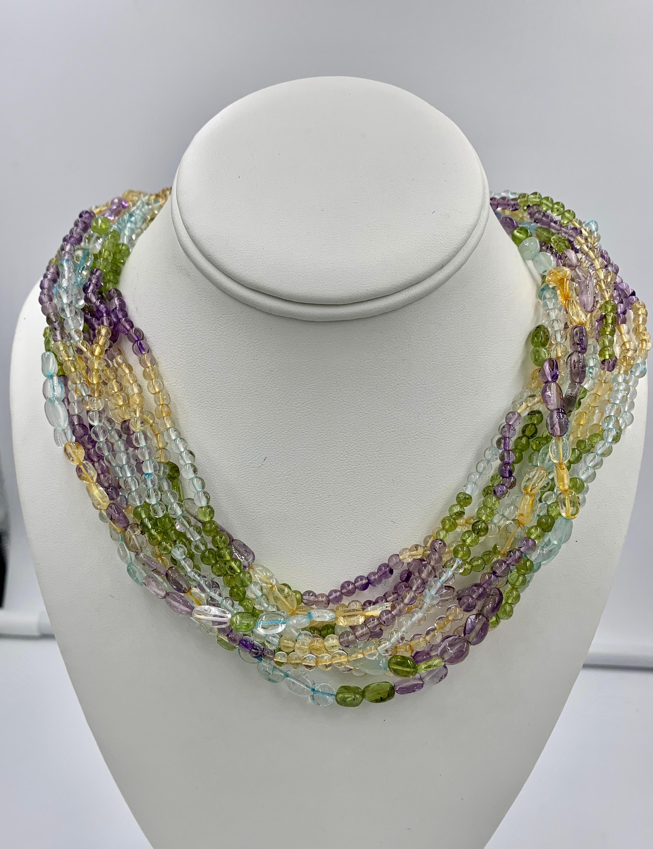 This is a fabulous Multistrand Multicolored Bead Torsade Necklace with eleven strands of amethyst, peridot, citrine & aquamarine beads with a 14 Karat Gold clasp.  The stunning Multi Gem Necklace is set with round and oval Aquamarine, Citrine,