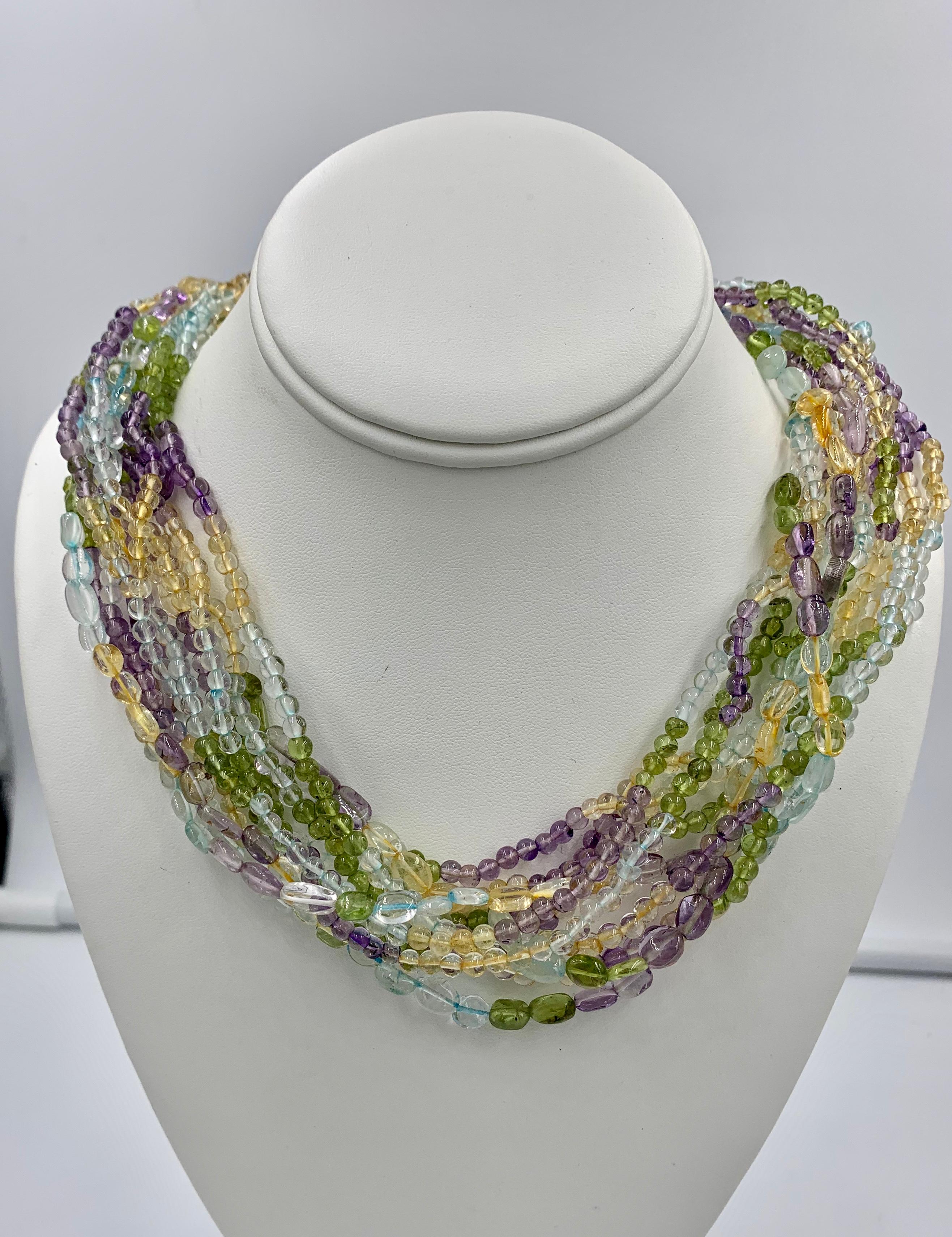 This is a fabulous Multi-strand Multicolored Bead Torsade Necklace with eleven strands of amethyst, peridot, citrine & aquamarine beads with a 14 Karat Gold clasp.  The stunning Multi Gem Necklace is set with round and oval Aquamarine, Citrine,