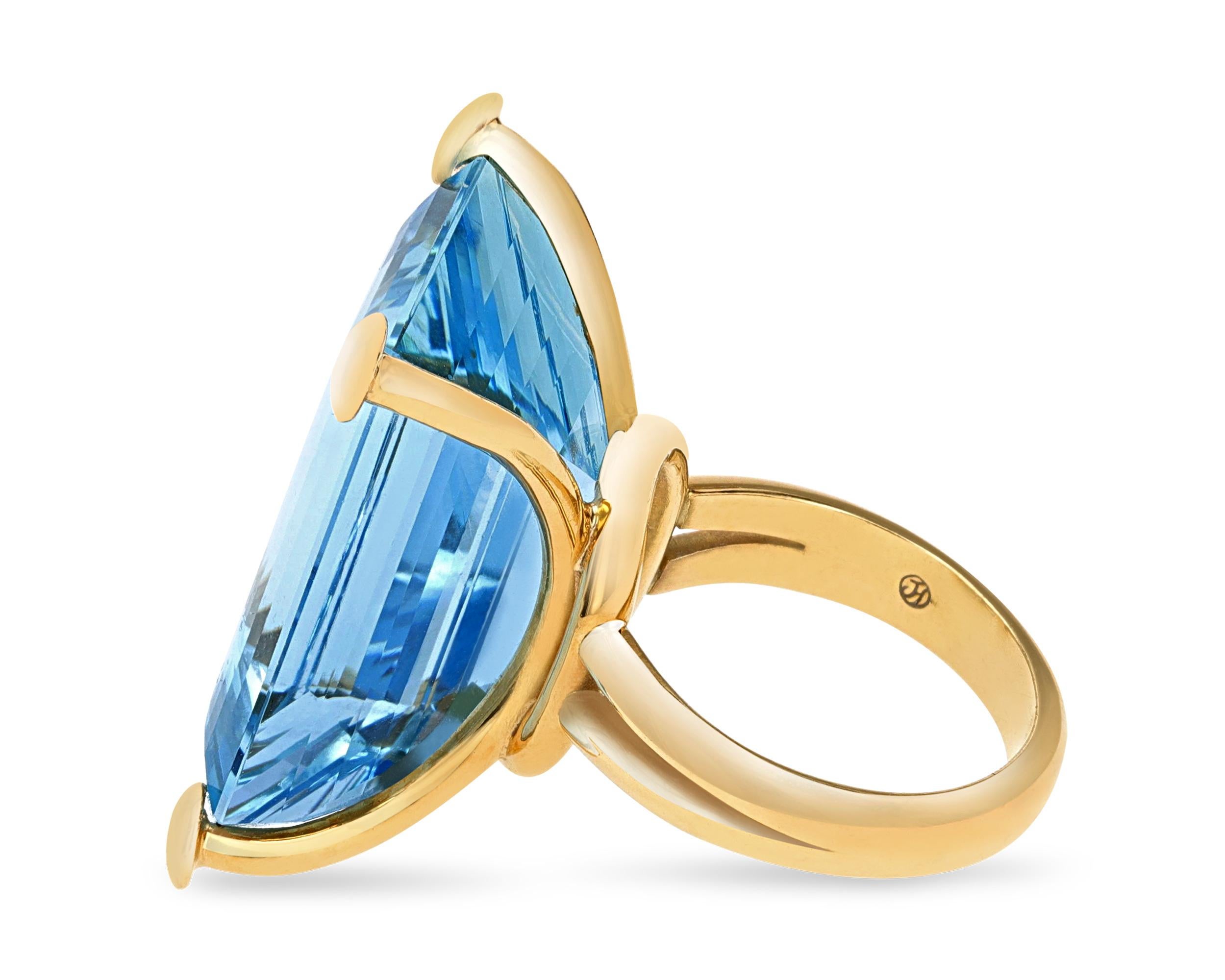 This striking ring features a 32.15 carat emerald-cut aquamarine. The gemstone's dazzling icy blue hue and clarity are emphasized by its regal cut and impressive size. The gemstone is set in a unique 18K yellow gold band with small spheres adorning