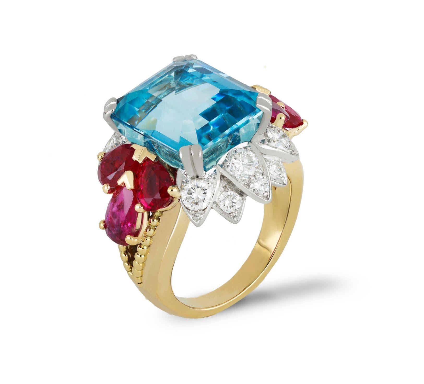 Aquamarine, ruby and diamond cocktail ring. Set with an octagonal emerald-cut natural aquamarine in an open back claw setting with an approximate weight of 8.22 carats, flanked by six pear shape cut Burmese rubies in open back claw settings with a