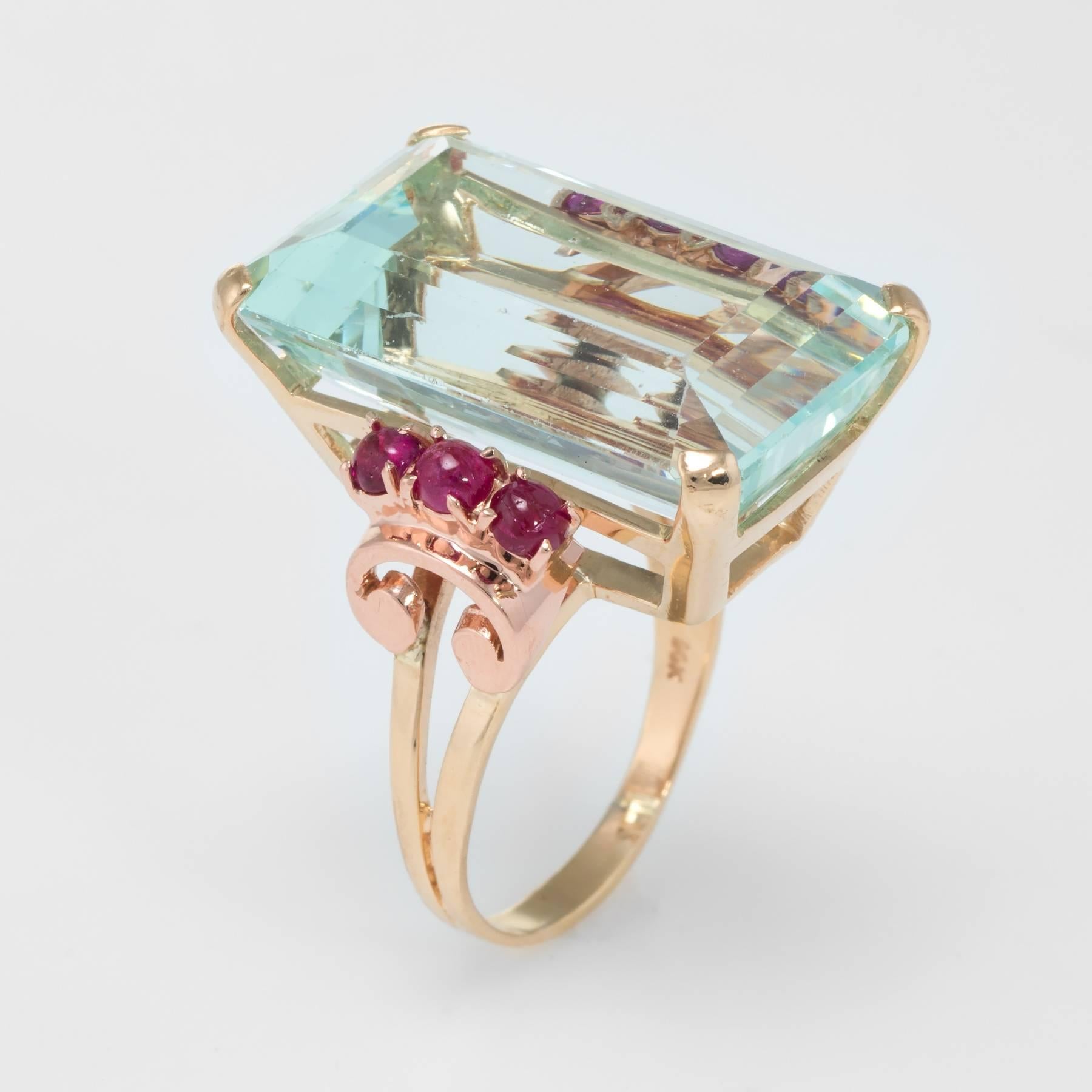 Bold and stylish retro cocktail ring (circa 1940s to 1950s), crafted in 14 karat yellow gold with rose gold accents. 

Centrally mounted emerald cut aquamarine measures 25mm x 16mm and is estimated at 40 carats, accented with an estimated 0.50
