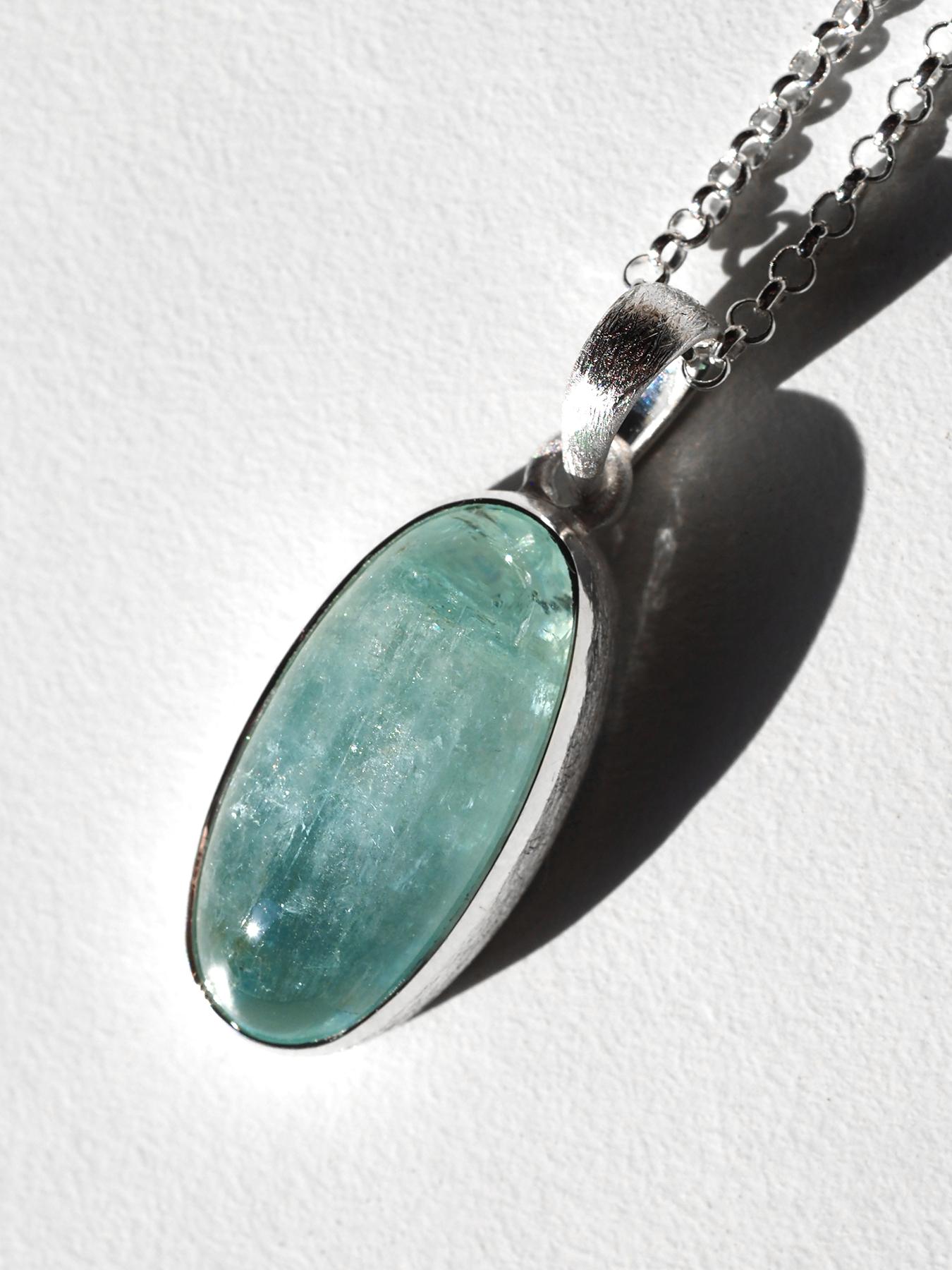 Este refinado colgante presenta una aguamarina brasileña natural engastada en plata de ley 925 con acabado mate, una composición que equilibra la sobriedad contemporánea con una sutil luminosidad. Cuidadosamente seleccionada por su claridad y suave