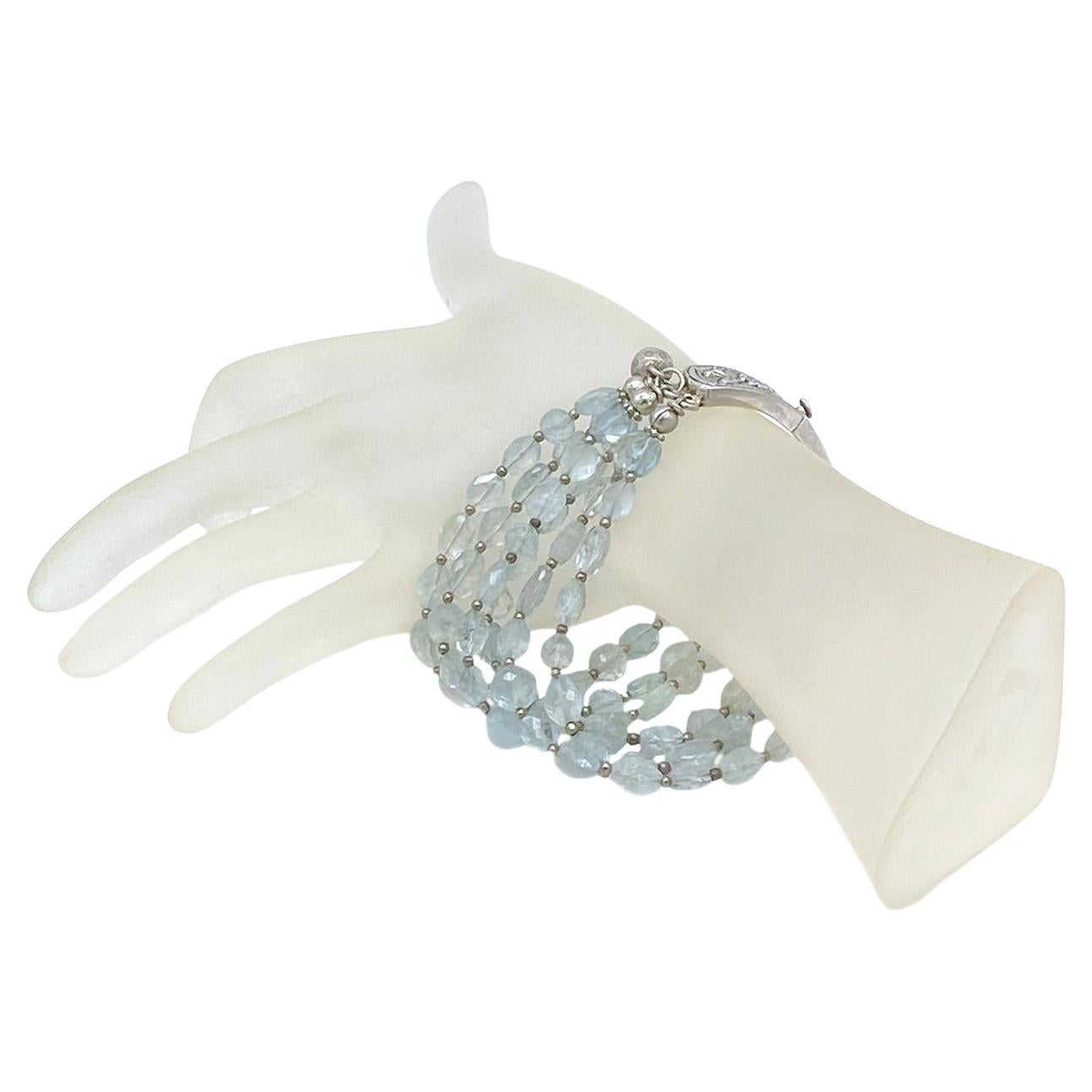 We created this multi-strand bracelet with faceted translucent aquamarines and sterling spacers. It comes with a one-of-a-kind, hand made sterling silver curved band box clasp and is accented with two hill tribe fine silver bells.

Our vintage