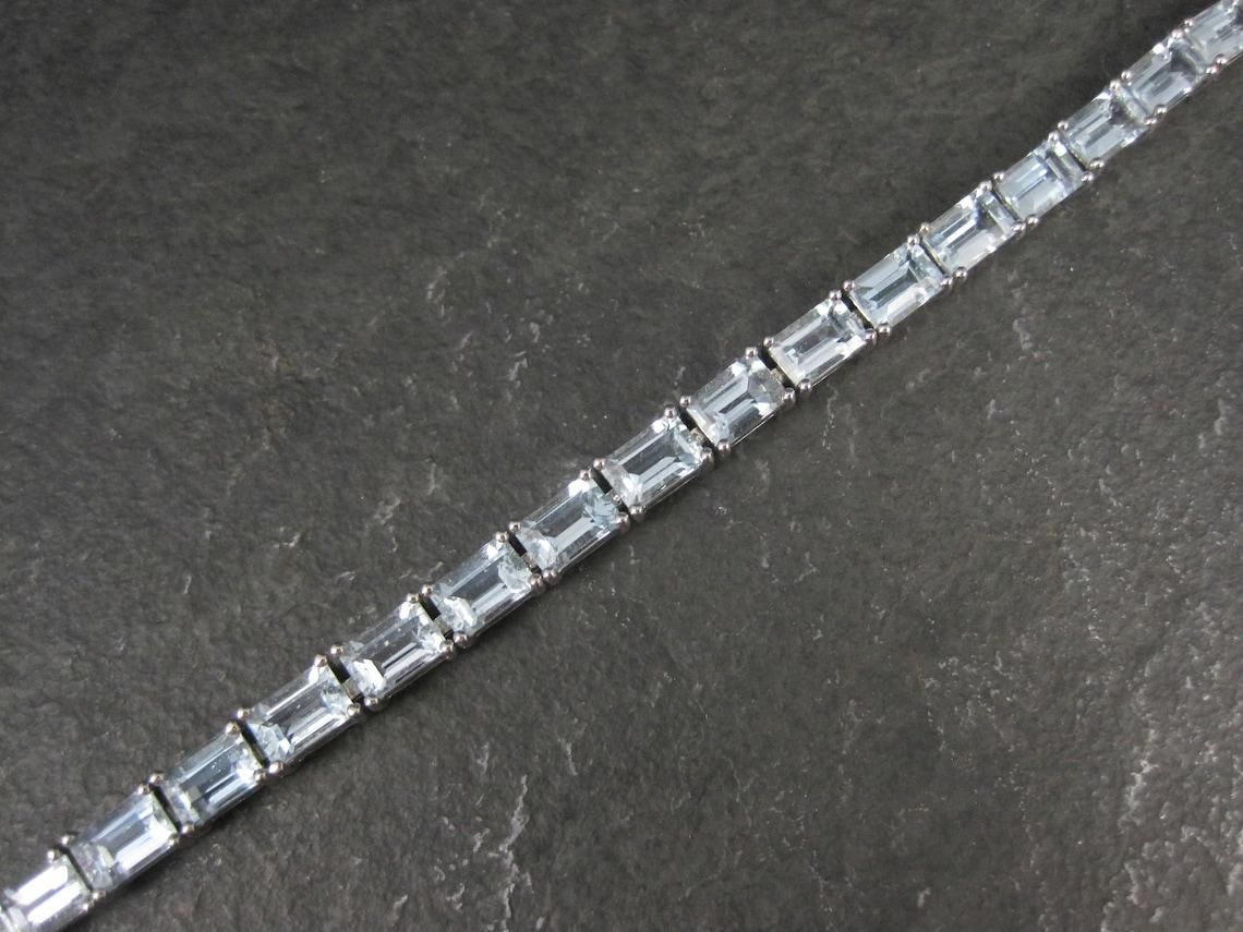 This gorgeous bracelet is sterling silver.
It features 27 emerald cut 4x6mm genuine aquamarine gemstones.

Measurements: 3/16 of an inch wide, 7 wearable inches

Condition: New Old Stock / Never Worn