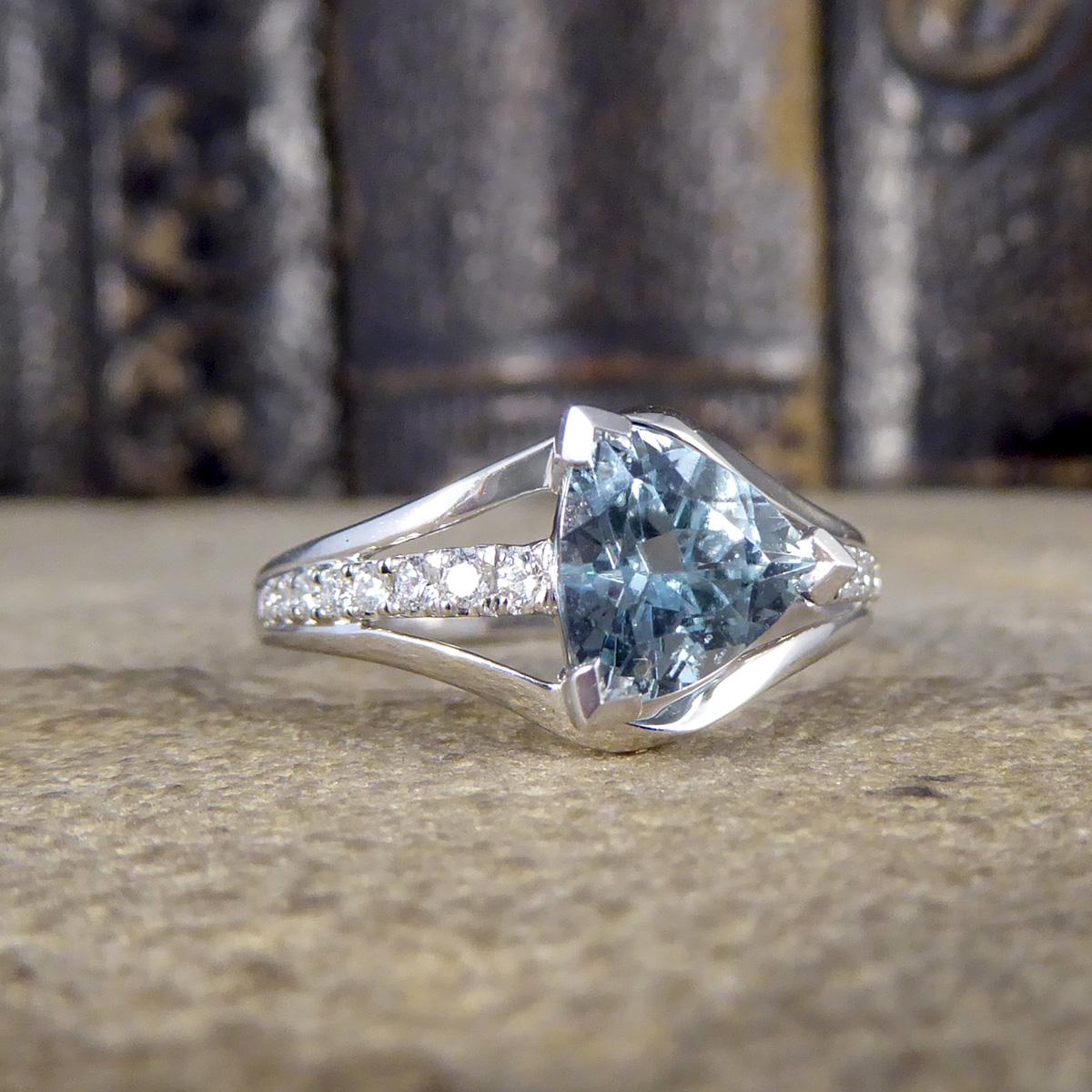 Dieser neue Ring enthält einen Aquamarin im Trillion-Schliff von 1,38 Karat mit einem hellen, leuchtend blauen Farbton in einer Eckfassung mit Reibung. Der Kopf des Rings hat eine drei-Stränge-Ästhetik mit der Mitte Strang voll Diamant mit insgesamt