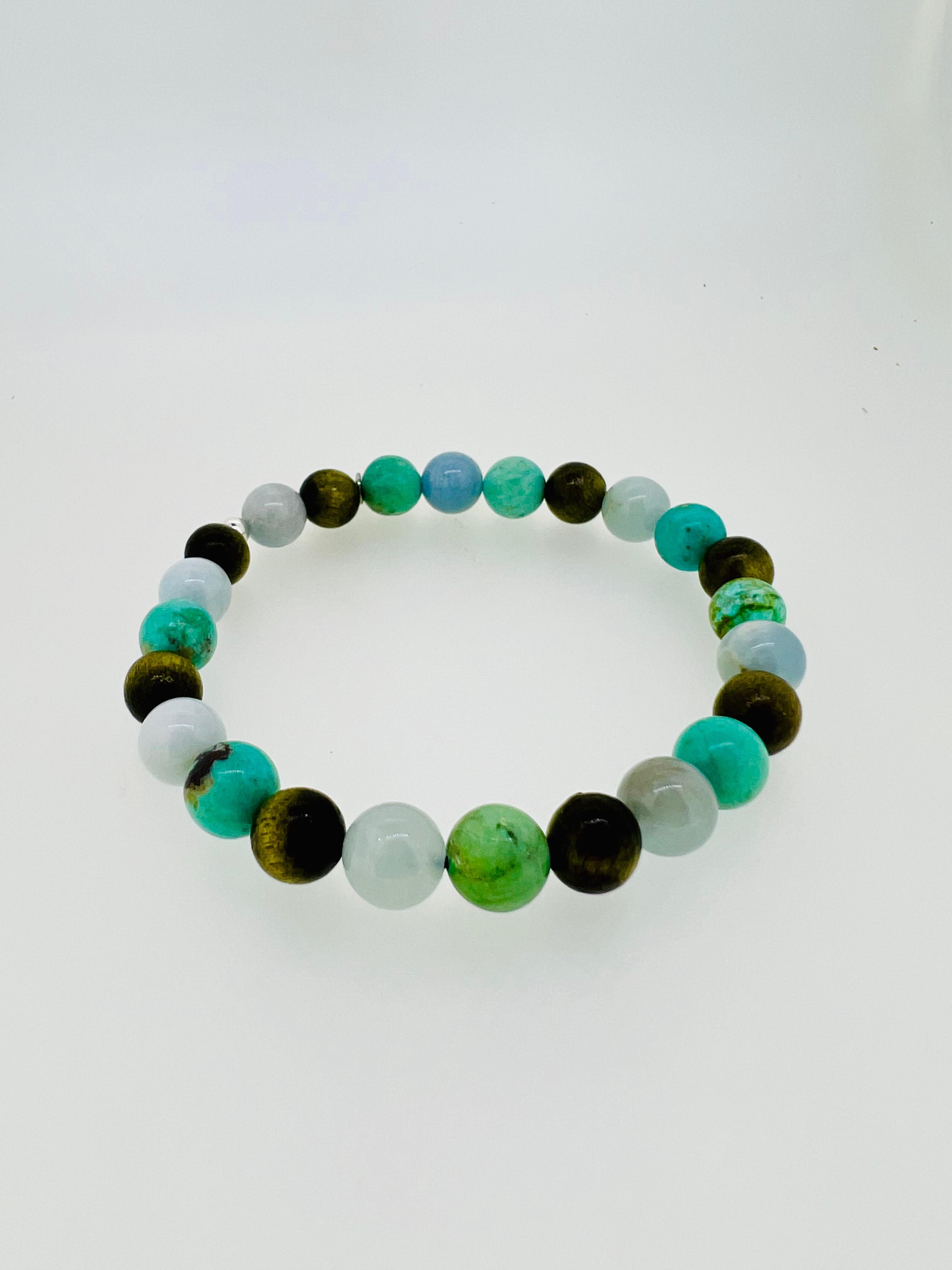Introducing a stunning men’s bracelet combining the tranquil beauty of 8mm aquamarine beads, untreated Peruvian turquoise in rich green-blue tones (8mm), and olive-green Phoebe Cat Eye wood. The olive hue of the wood perfectly complements the soft