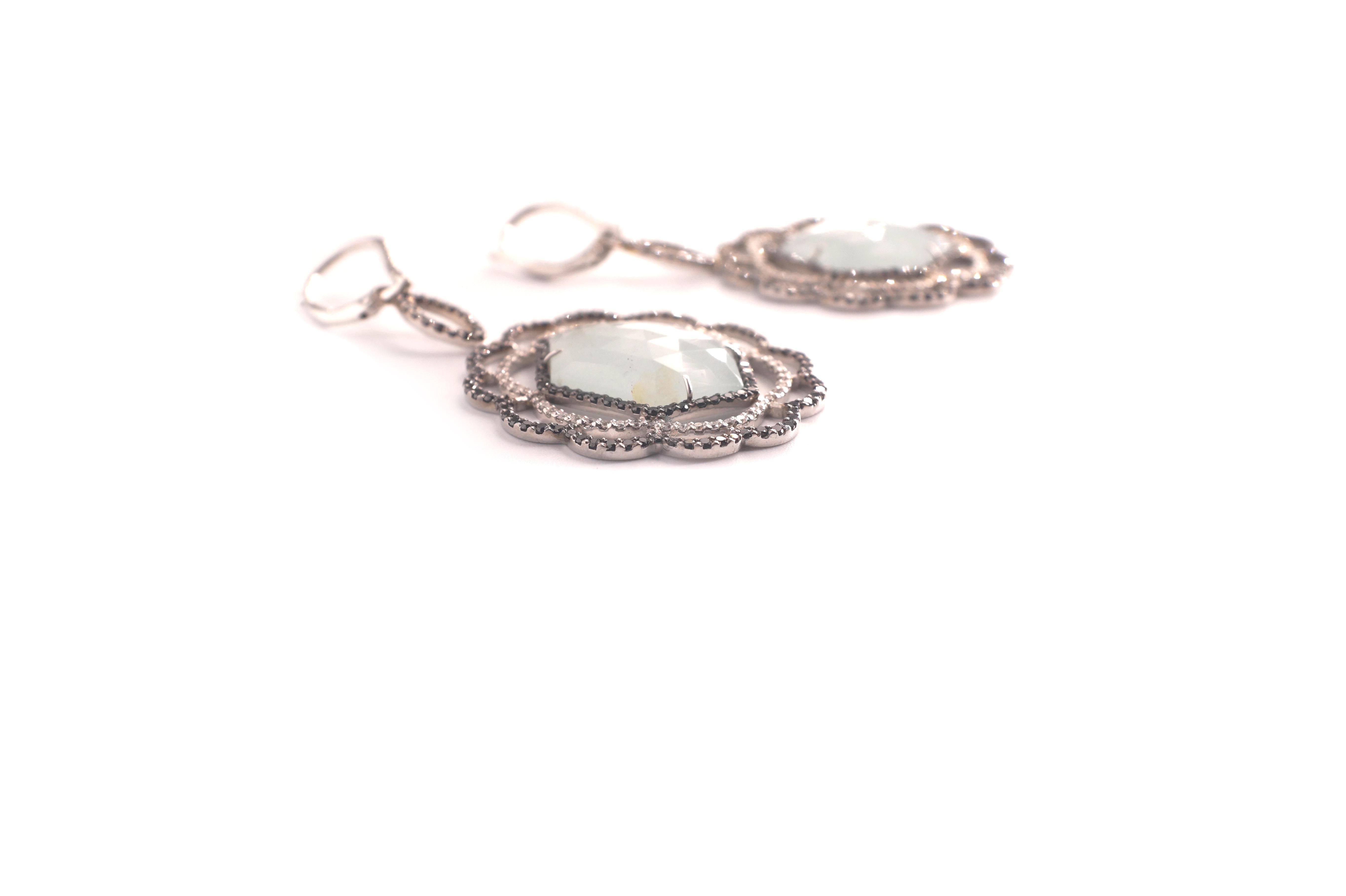 Nastasia Hexagon Aqua Diamond Eardrops
A pair of platinum, aquamarine, black and white diamond eardrops, each composed of a hexagonal aquamarine rose-cut as the center.  Around this gemstone, one finds a fine black diamond frame, followed by two