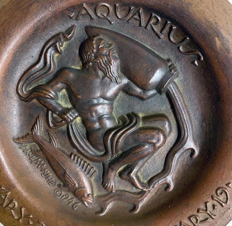 Boldly and brilliantly sculpted in high relief, this depiction of Aquarius -- the water bearer, a mystical healer who bestows water upon the land -- shows a bearded, nude male figure pouring water from a large urn, with a fish beneath him. This rare