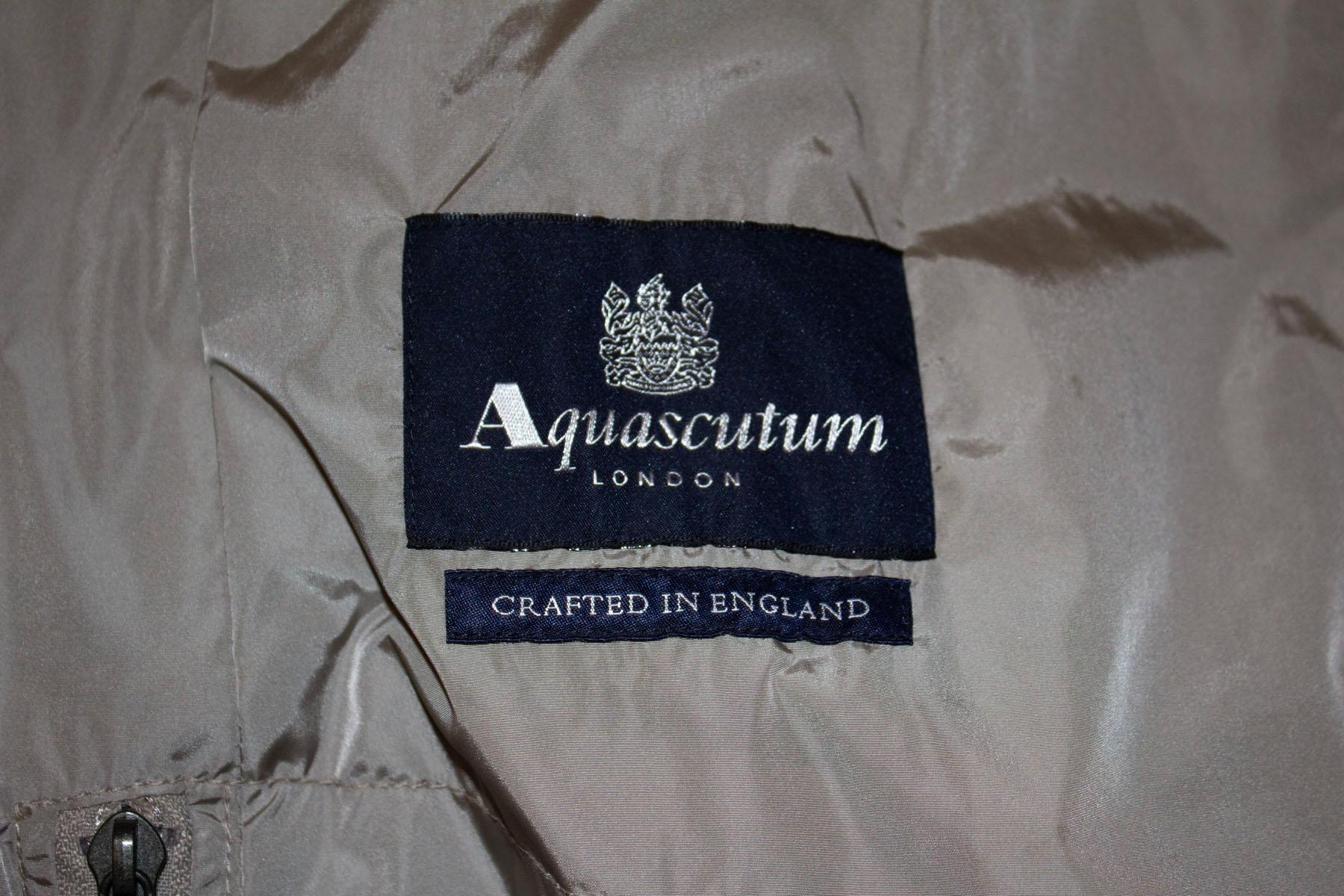 A short and sassy raincoat by leading British brand Aquascutum. The coat is in a pretty grey /silver colour and has a self fabric belt, epaulettes, a pocket on either side plus and internal pocket.  UK size 14, measurements Bust 39'', length 38''