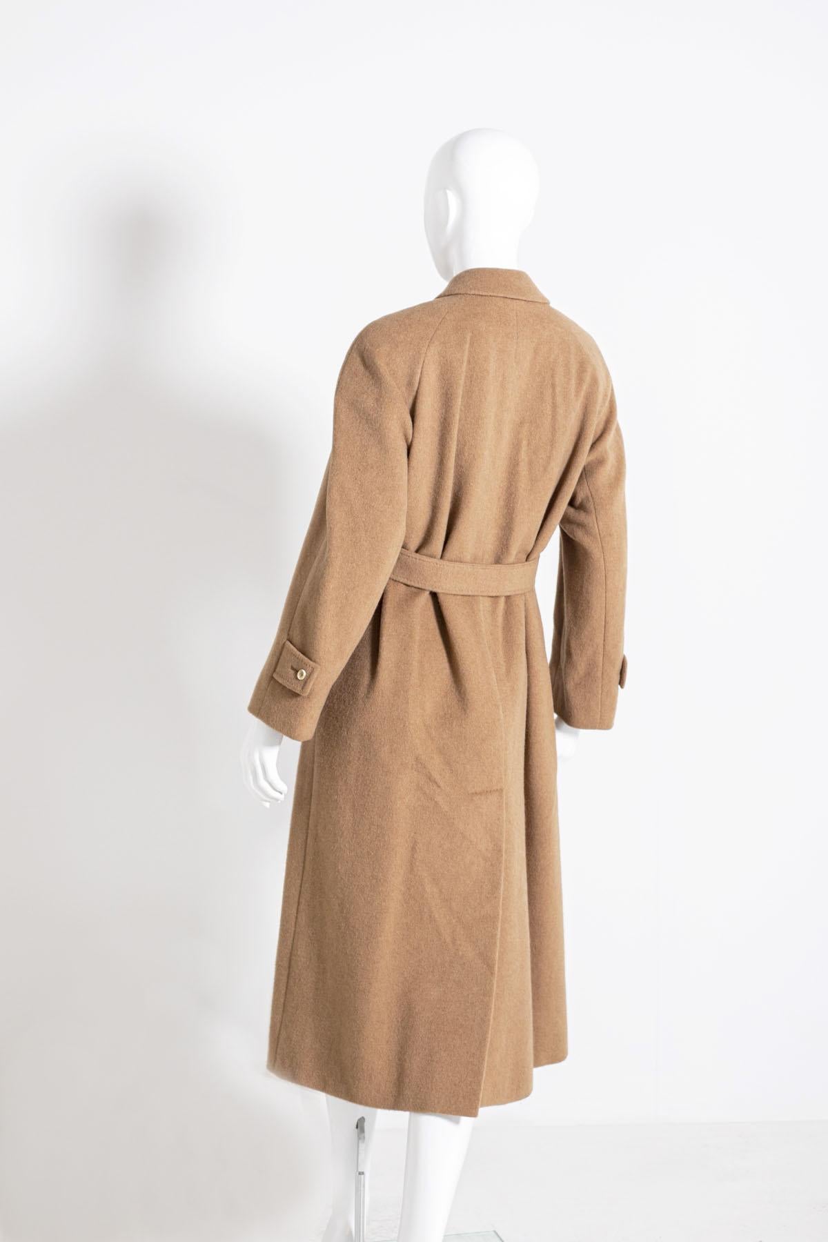 Manteau Aquascutum pour femme des années 90, couleur camel, fait de 100% pur Cachemire. 
Ligne classique, avec cinq boutons sur le devant et deux poches confortables, longueur cheville avec ceinture assortie réglable. L'intérieur est doublé en 100%