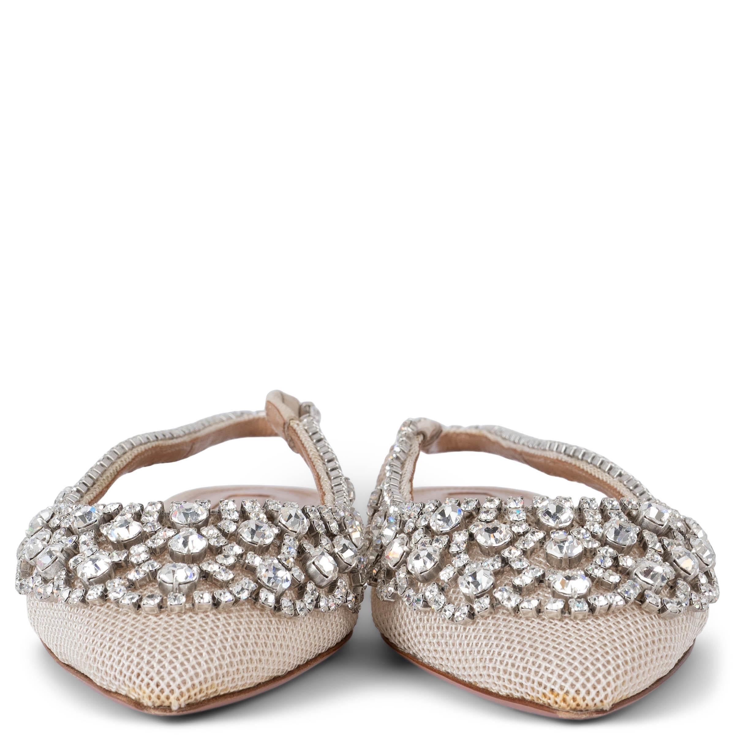 These 100% authentic Aquazzura Marahani slingback flats are crafted from beige mesh and are embellished with clear crystals reminiscent of Maharaja jewelry. Designed with an elegant almond toe, these flats offer a refined and luxurious look, perfect