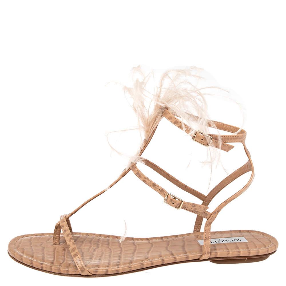 These Aquazzura sandals are stylish and easy to wear. They have been crafted from snake-embossed leather and come in a beige hue. it has feather trims, T-straps, ankle straps and leather soles.

