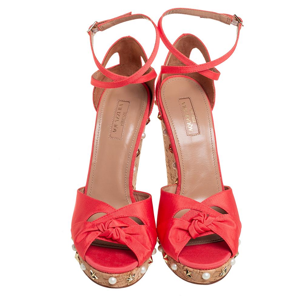 Stay in style with this stunning pair from Aquazzura! Beautifully crafted from fabric, these ankle strap sandals carry open toes, cut-out details, and embellished wedge heels. Get set to waltz around in this lovely coral orange pair!

Includes: