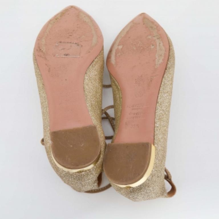 You're sure to win hearts with these gorgeous ballet flats from Aquazzura. In a classy metallic gold-hued exterior made from glitter, the flats carry pointed toes, lace-ups, and comfortable leather insoles. Be it with dresses or jeans, these flats
