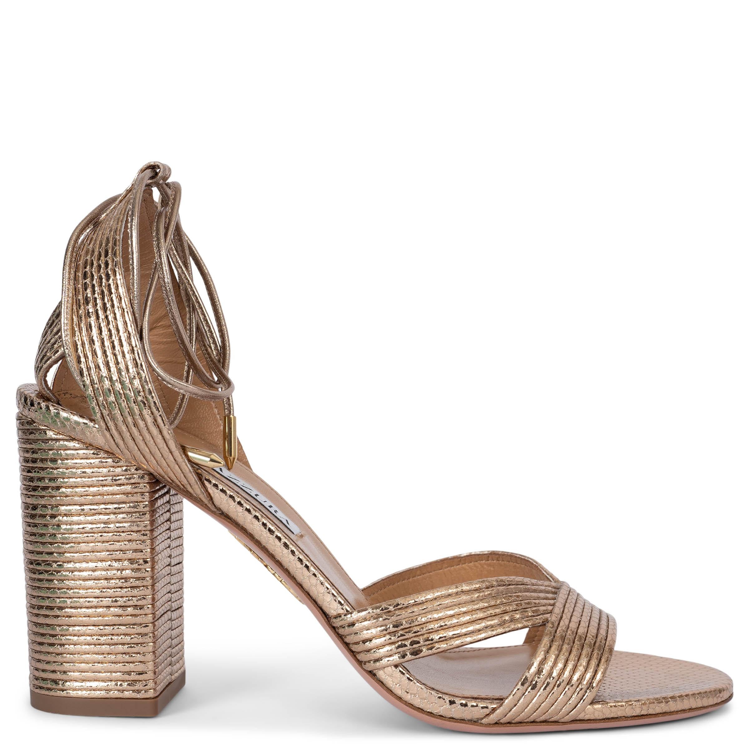 Estas sandalias Ari Metallic 100% auténticas de Aquazzura están fabricadas en Italia con suave y lujosa piel en un refinado tono dorado cálido. Esta impresionante iteración metálica presenta un tacón alto en bloque, que ofrece estilo y estabilidad.