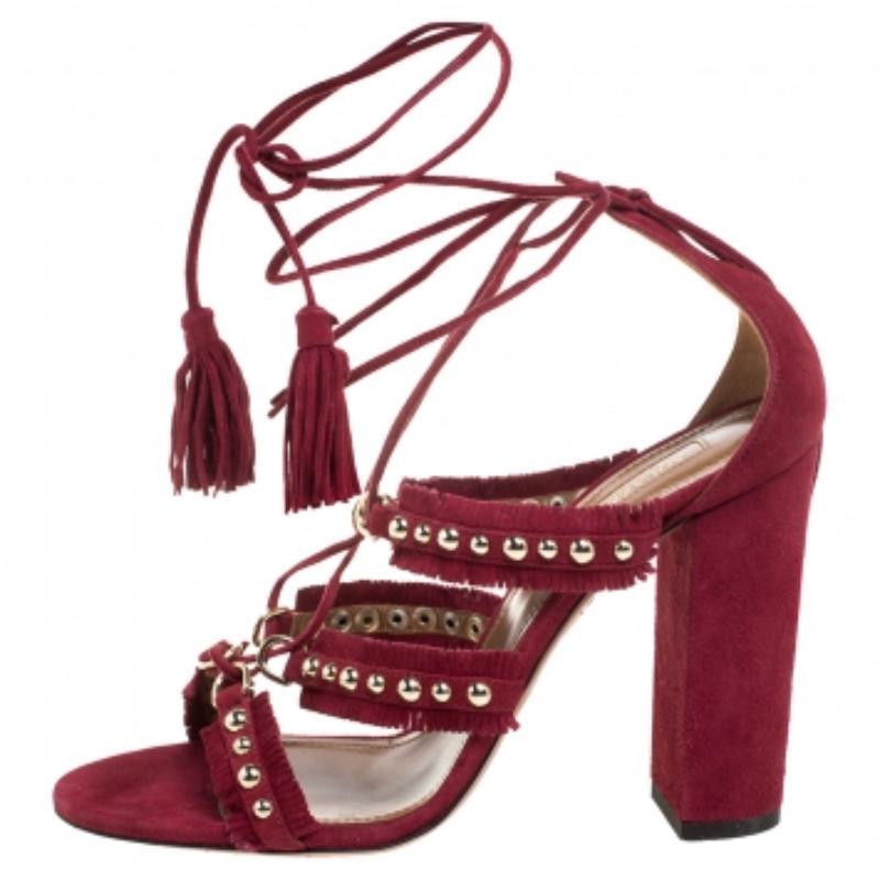 These Aquazurra sandals are simply amazing! The burgundy sandals are crafted from suede in a strappy layout. They feature studded straps, fringe trims, tassel-detailed tie-ups at the ankles, and block heels. They are sure to adorn your feet with
